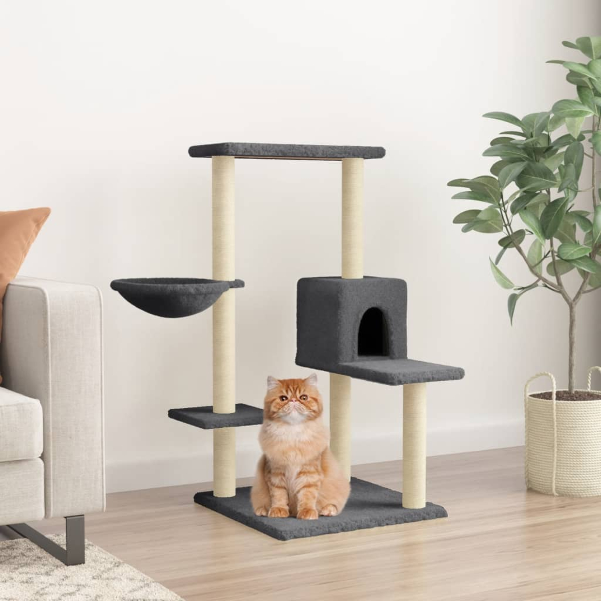 Eine Katze sitzt auf einem grauen Kratzbaum. Im Hintergrund sind ein Sofa und eine Pflanze zu sehen. Die Katze ist orange.