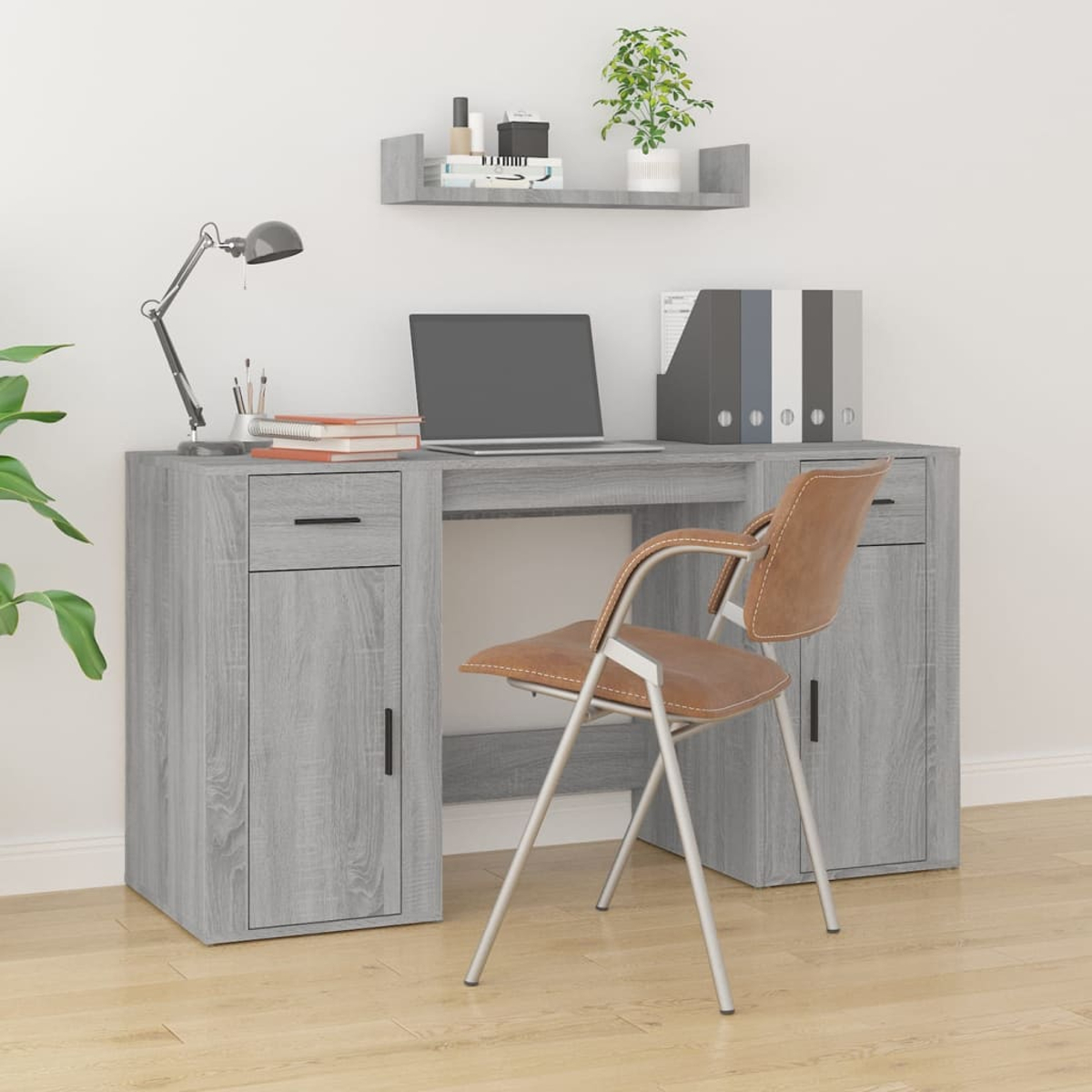 Ein grauer Schreibtisch mit Laptop, Lampe und Stuhl. Auf einem Regal stehen Pflanzen und Büromaterial. Holzfußboden und weiße Wand.