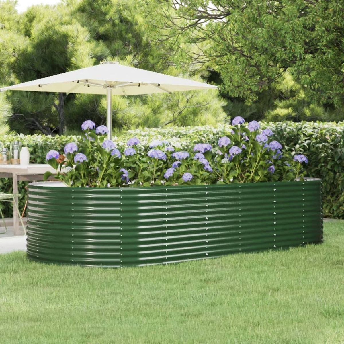 Ein grüner Wellblech-Pflanzkübel mit lila Blumen, einem weißen Sonnenschirm und grünem Gras in einem Garten.