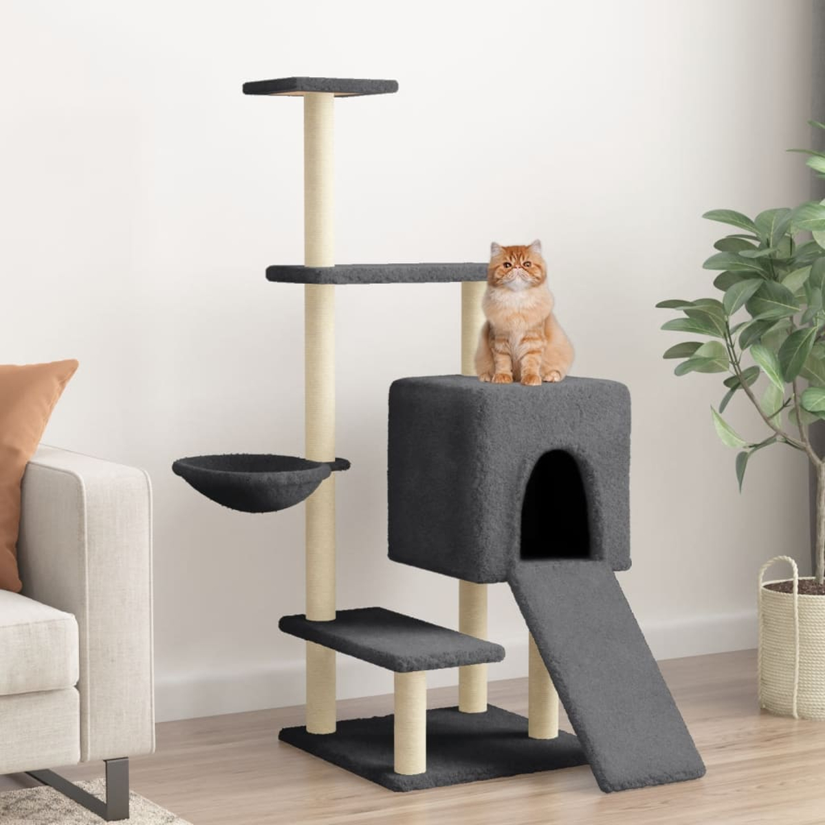Eine Katze sitzt auf einem grauen Kratzbaum. Der Baum hat mehrere Ebenen, ein Haus und eine Rampe. Rechts ist eine Pflanze.