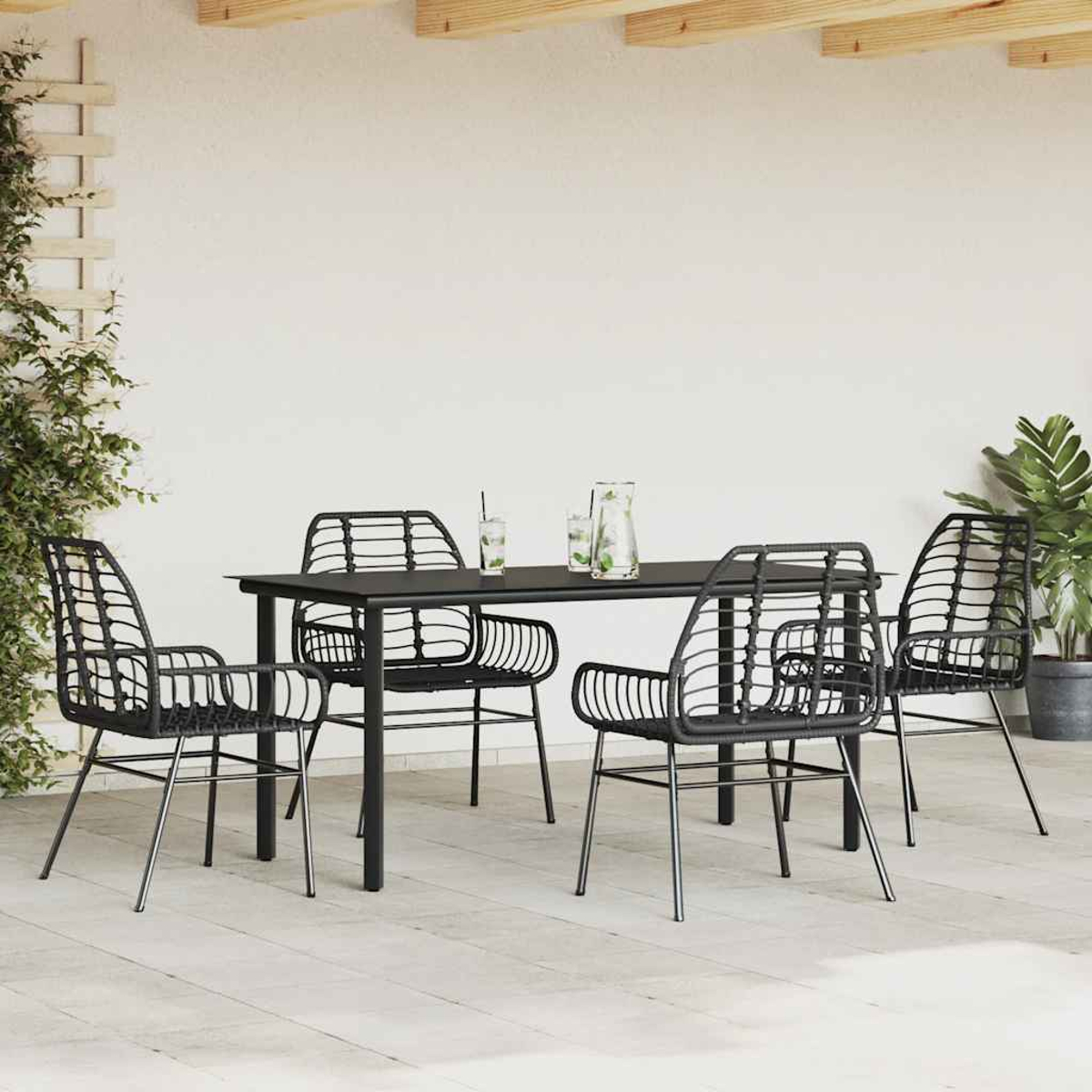 Eine Szene auf der Terrasse mit einem schwarzen Tisch und Stühlen. Getränke stehen auf dem Tisch. Pflanzen und ein Spalier sind an der Seite.