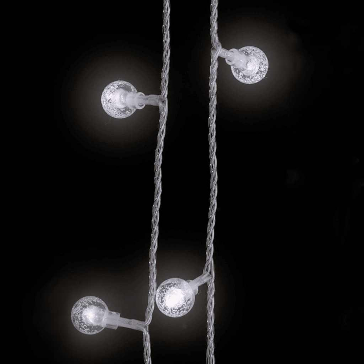 Kette aus leuchtenden, runden Lichtern an silbernem Draht vor schwarzem Hintergrund. Vier Lichter sind sichtbar, mit hellen Zentren.