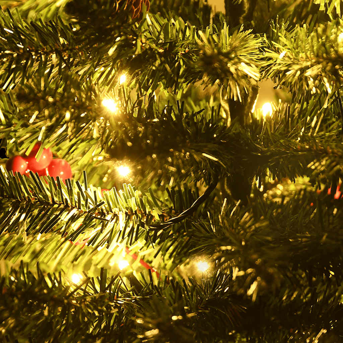 Nahaufnahme eines Weihnachtsbaums mit grünen Nadeln, kleinen Lichtern und roten Beeren. Die Lichter leuchten und die Szene ist warm.