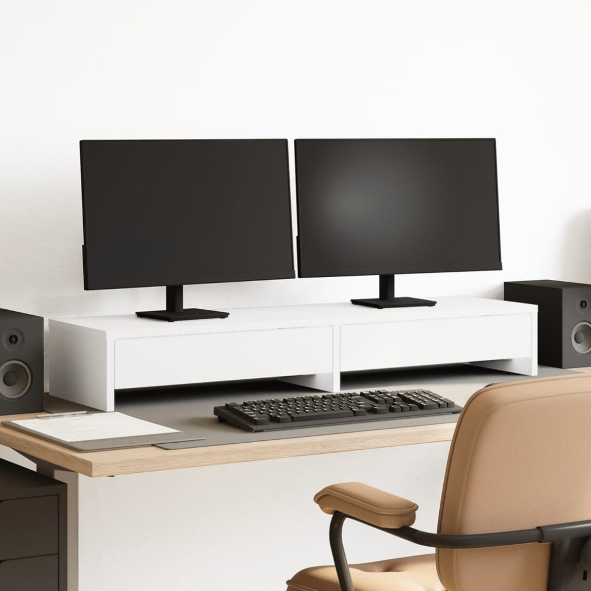 Zwei schwarze Monitore auf einem weißen Ständer. Eine Tastatur, Lautsprecher und ein beiger Stuhl befinden sich im Vordergrund. Der Hintergrund ist eine weiße Wand.