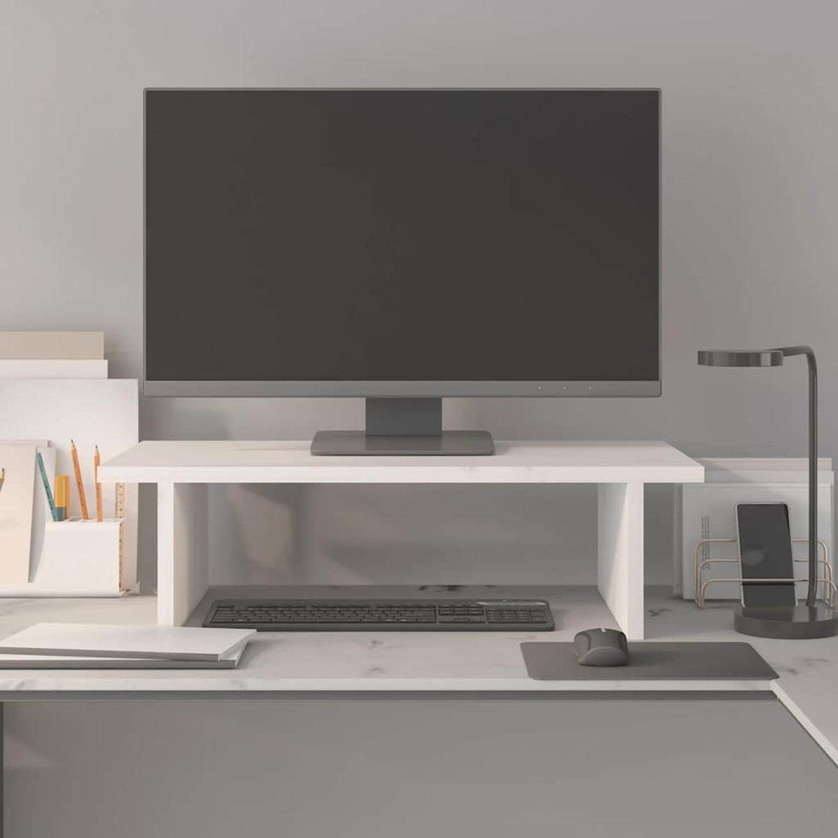 Moderne Schreibtischeinrichtung. Ein großer Monitor steht auf einem weißen Ständer. Tastatur, Maus, Lampe, Telefon und Schreibwaren sind angeordnet.