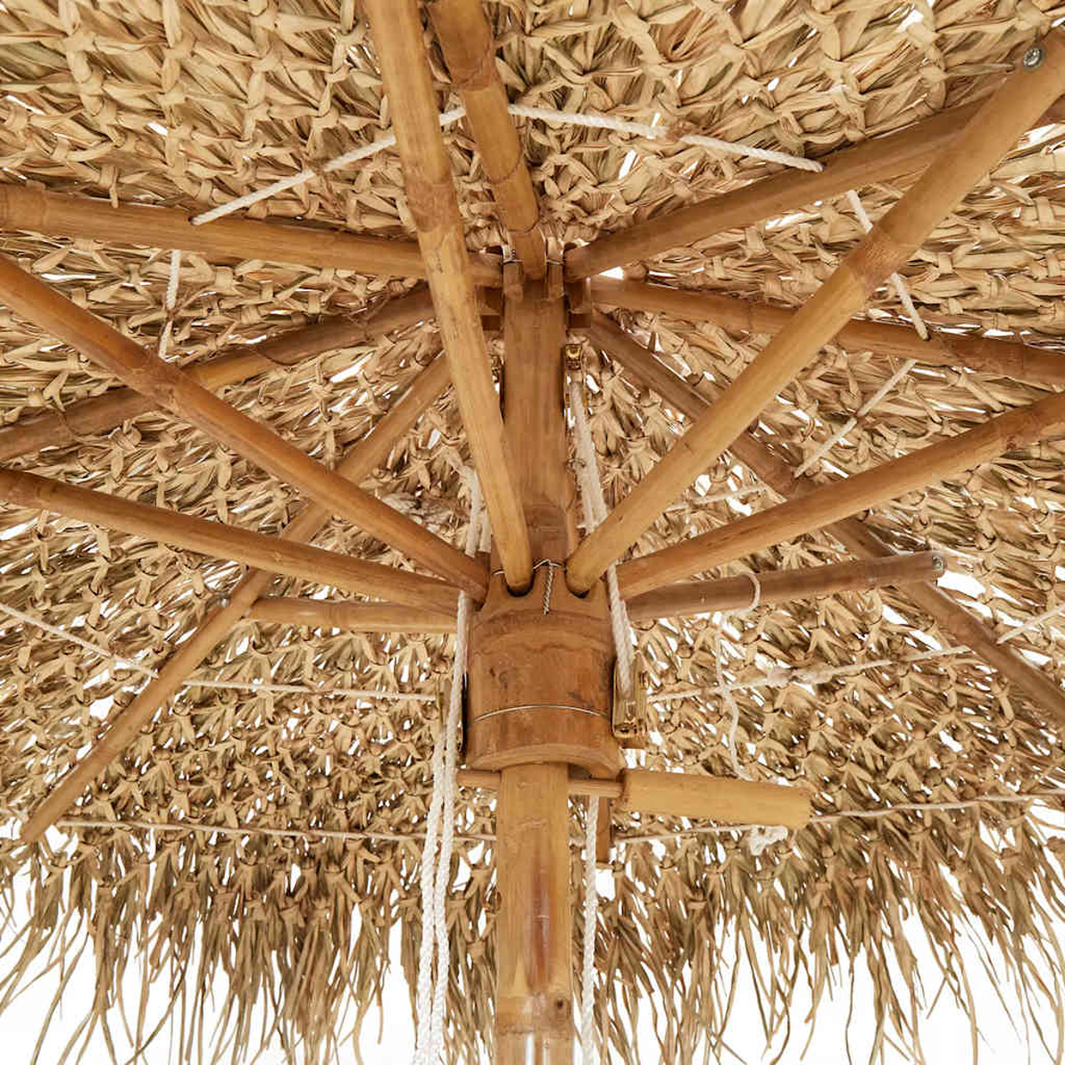 Vista interna di un ombrellone da spiaggia. Ha un tetto di paglia sostenuto da travi di legno e sono visibili corde bianche.