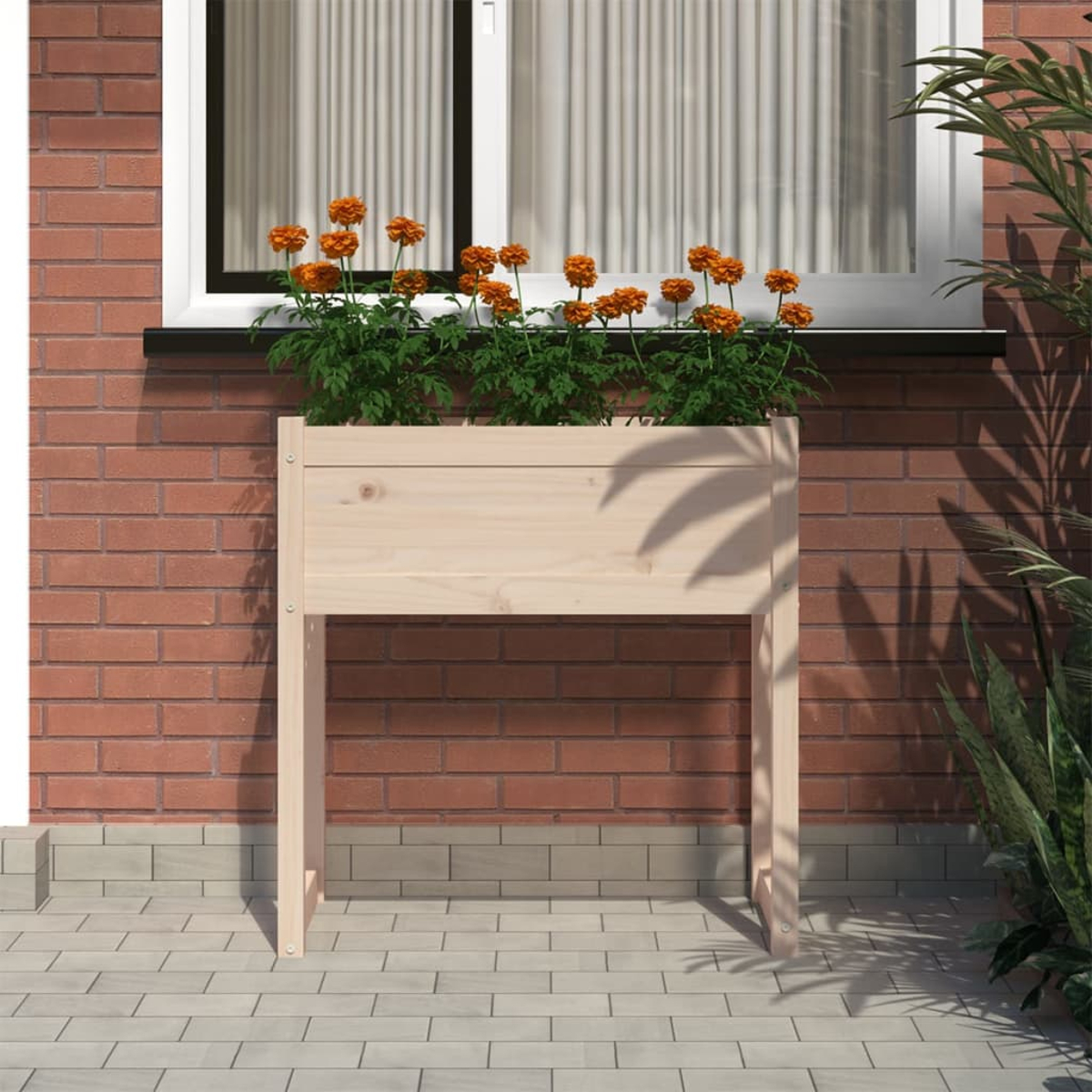 Ein hölzerner Pflanzkasten mit orangefarbenen Blumen steht unter einem Fenster. Eine Backsteinmauer bildet den Hintergrund. Grüne Pflanzen rechts.