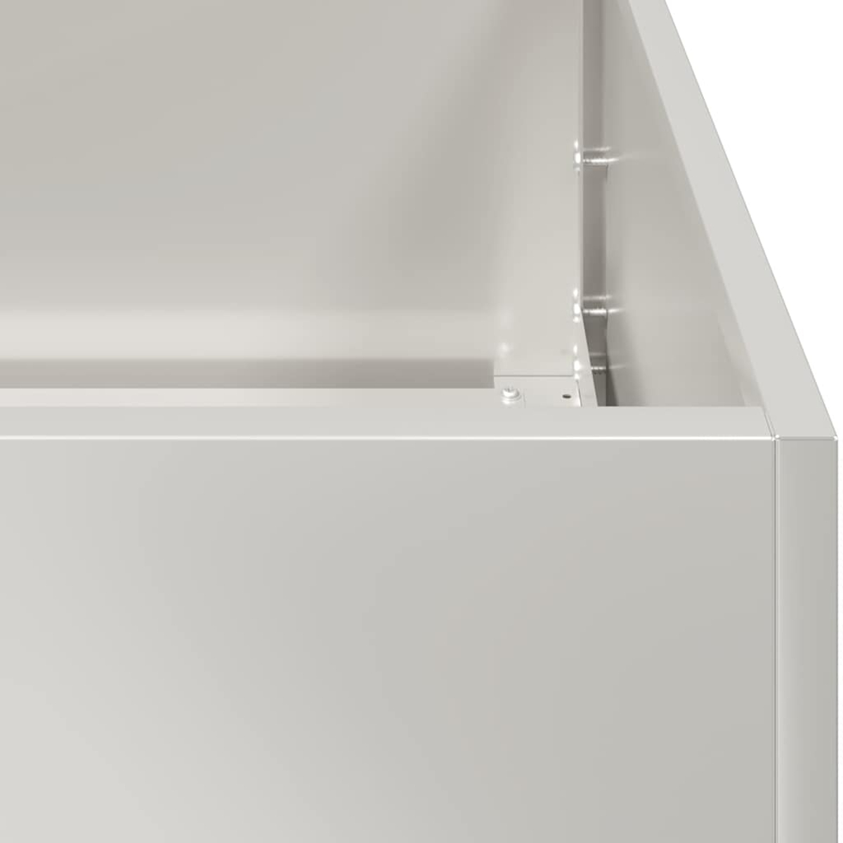 Primo piano di una scatola di metallo grigio chiaro. Sono visibili bordi, angoli e rivetti. La scatola è vuota e ha superfici pulite.