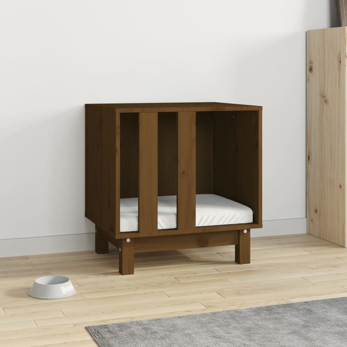 Ein braunes Hundehäuschen mit weißem Bett vor weißer Wand. Eine Futterschüssel und ein Teppich sind zu sehen.