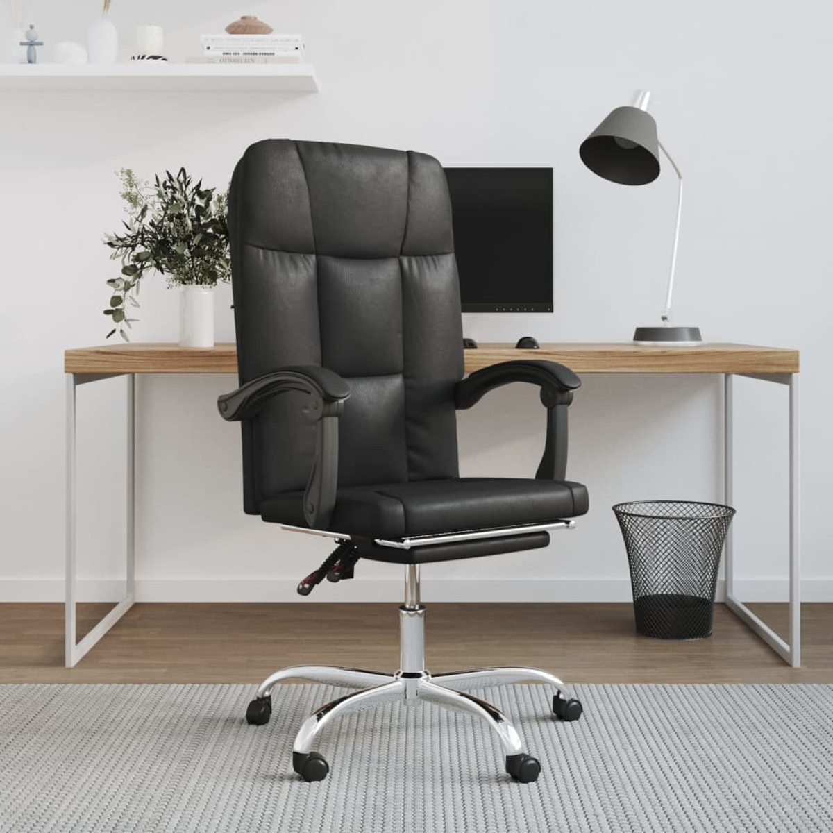 Schwarzer Leder-Bürostuhl vor einem Schreibtisch mit Lampe, Computer und Mülleimer. Pflanzen im Hintergrund.