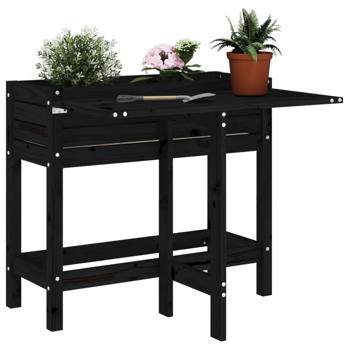 Schwarze Holz-Pflanzbank mit Pflanzen in Töpfen. Eine Kelle liegt auf dem Tisch. Pflanzen umfassen grüne und rosa Blumen und Farne.