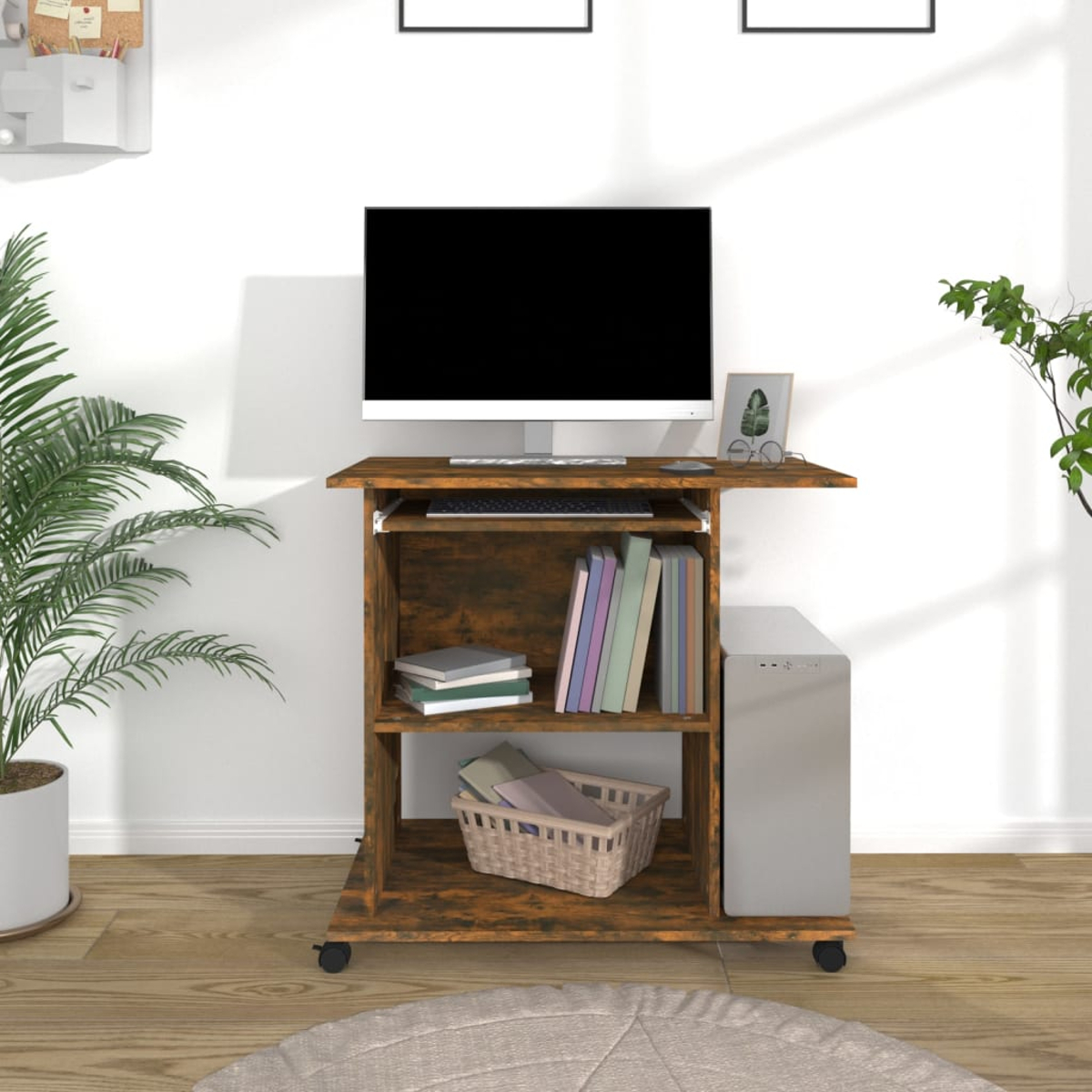 Ein Computertisch mit Monitor, Tastatur, Büchern und einem Computerturm. Er hat Räder und einen Weidenkorb.