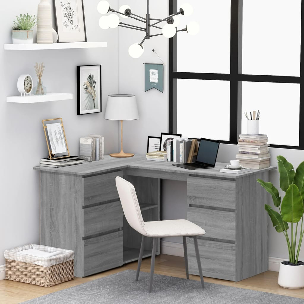 Ein grauer L-förmiger Schreibtisch mit Laptop, Büchern und Lampe. Davor steht ein weißer Stuhl. Im Hintergrund ein Fenster.