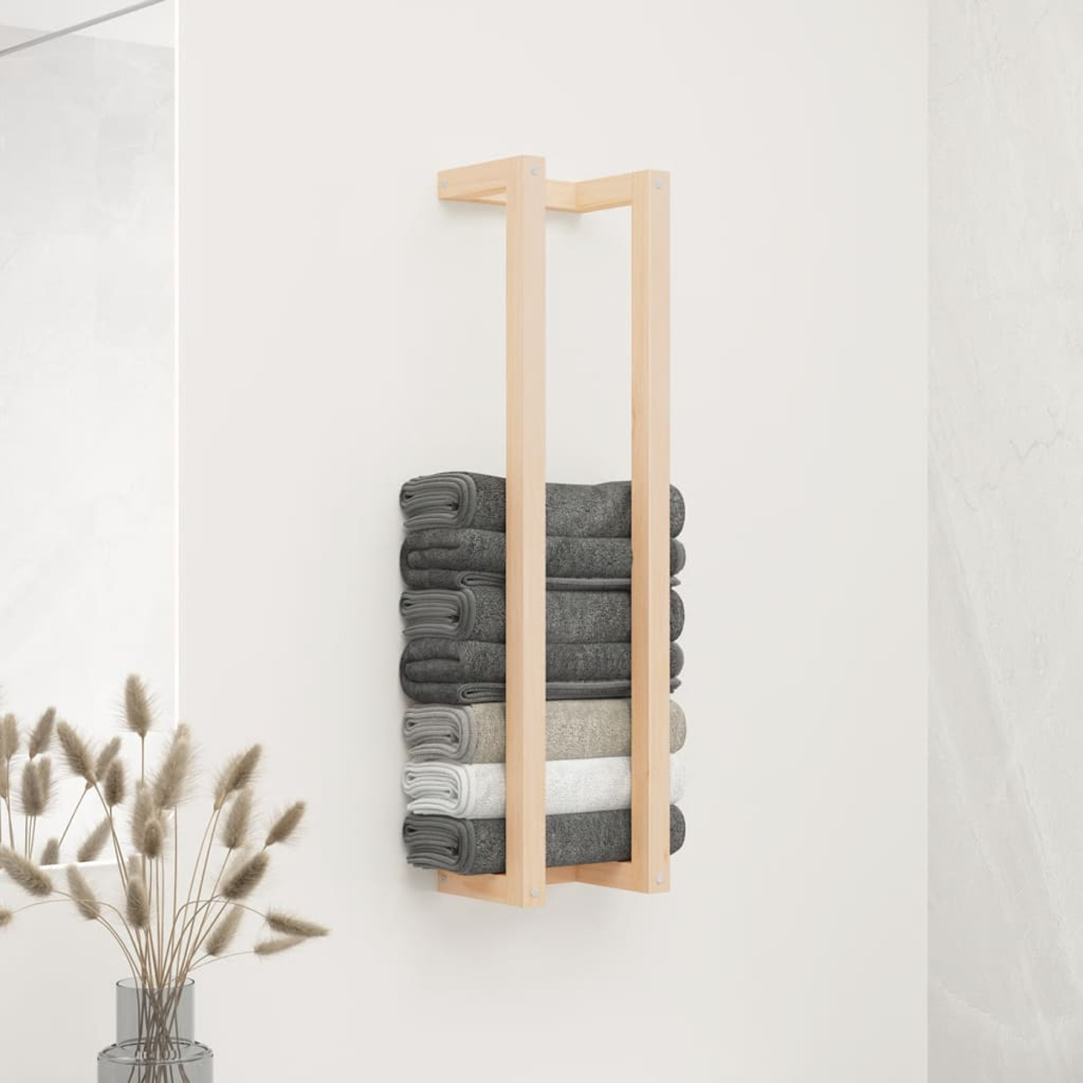 Ein hölzernes Handtuchregal an einer weißen Wand hält gefaltete graue, beige und weiße Handtücher. Getrocknete Pflanzen in einer Vase links.