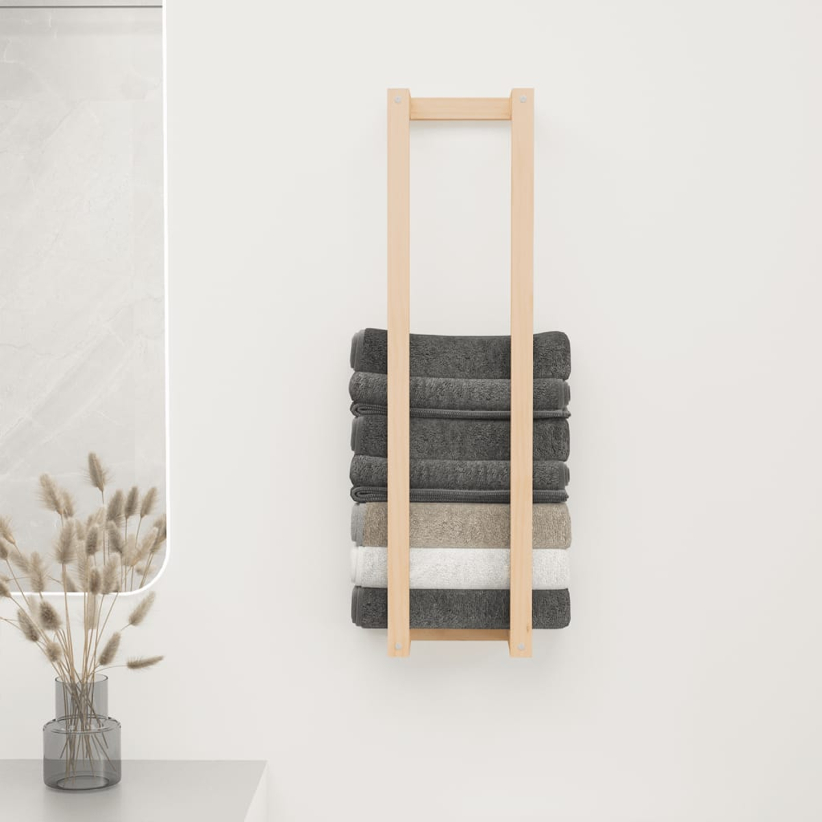 Ein Holzhandtuchhalter mit gestapelten Handtüchern in verschiedenen Grau- und Weißtönen, an einer weißen Wand. Eine Vase mit Schilf ist daneben.