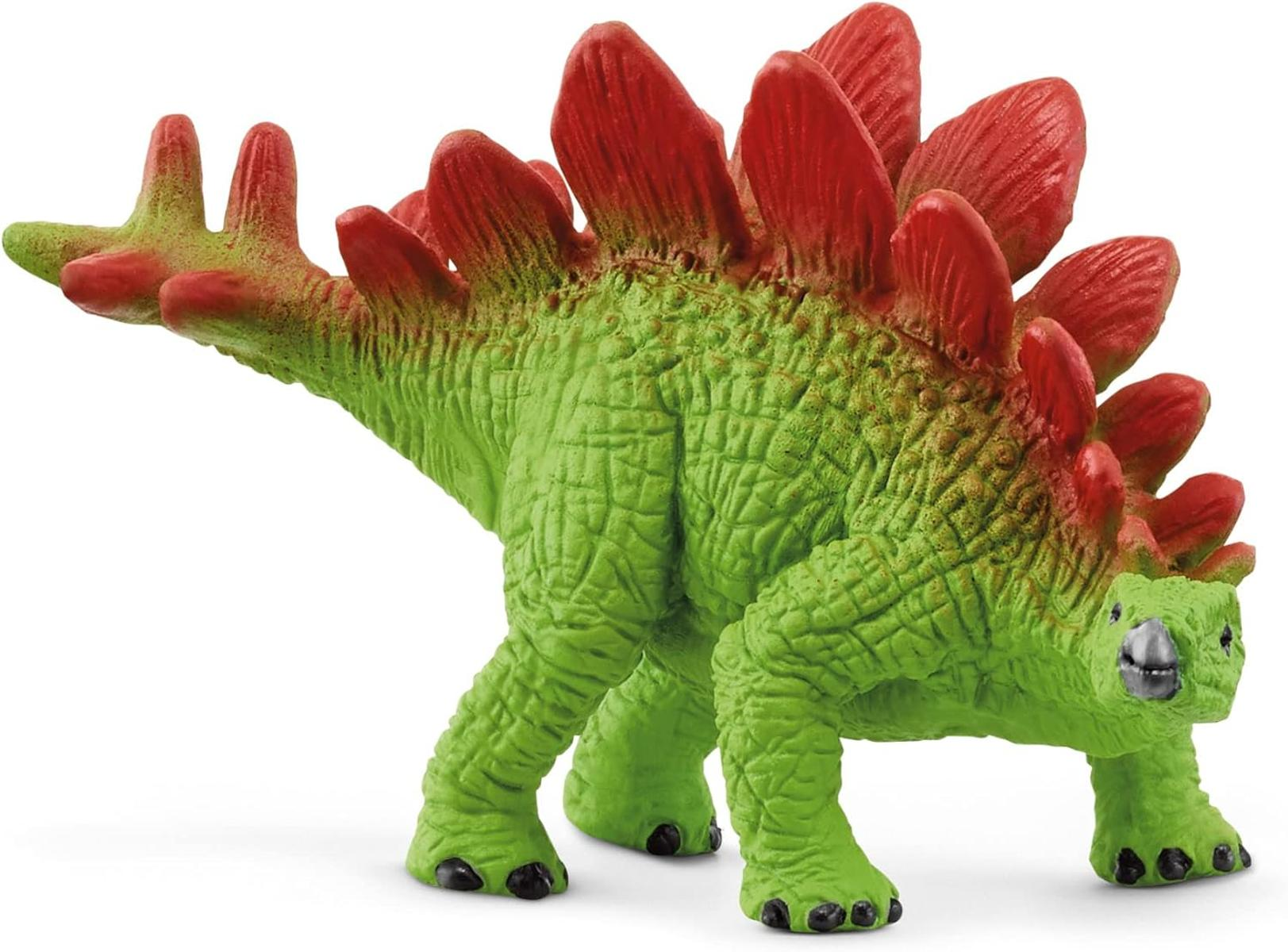 Ein grünes Stegosaurus-Spielzeug mit roten Platten auf dem Rücken steht. Es hat schwarze Füße und einen kleinen Kopf.
