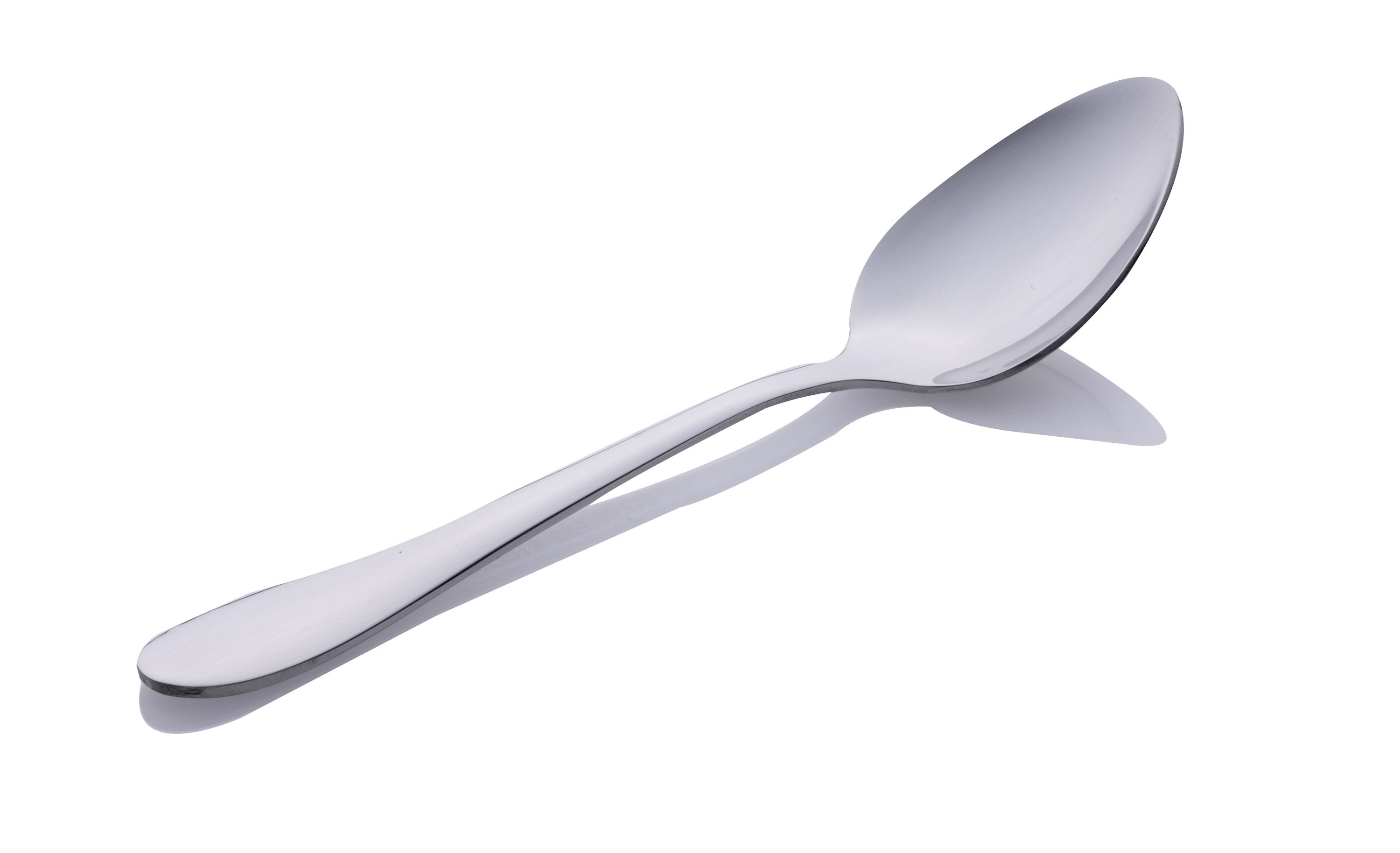 A shiny, silver spoon lies on a white surface. It is angled to the right, casting a shadow.