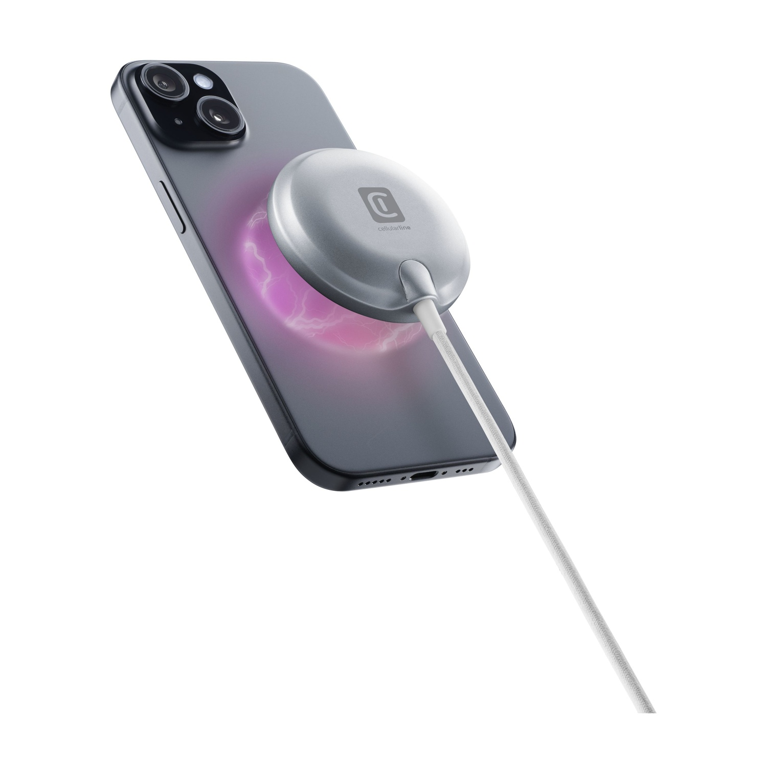 Szary smartfon z dołączoną srebrną ładowarką bezprzewodową. Ładowarka jest podłączona do białego kabla na białym tle.