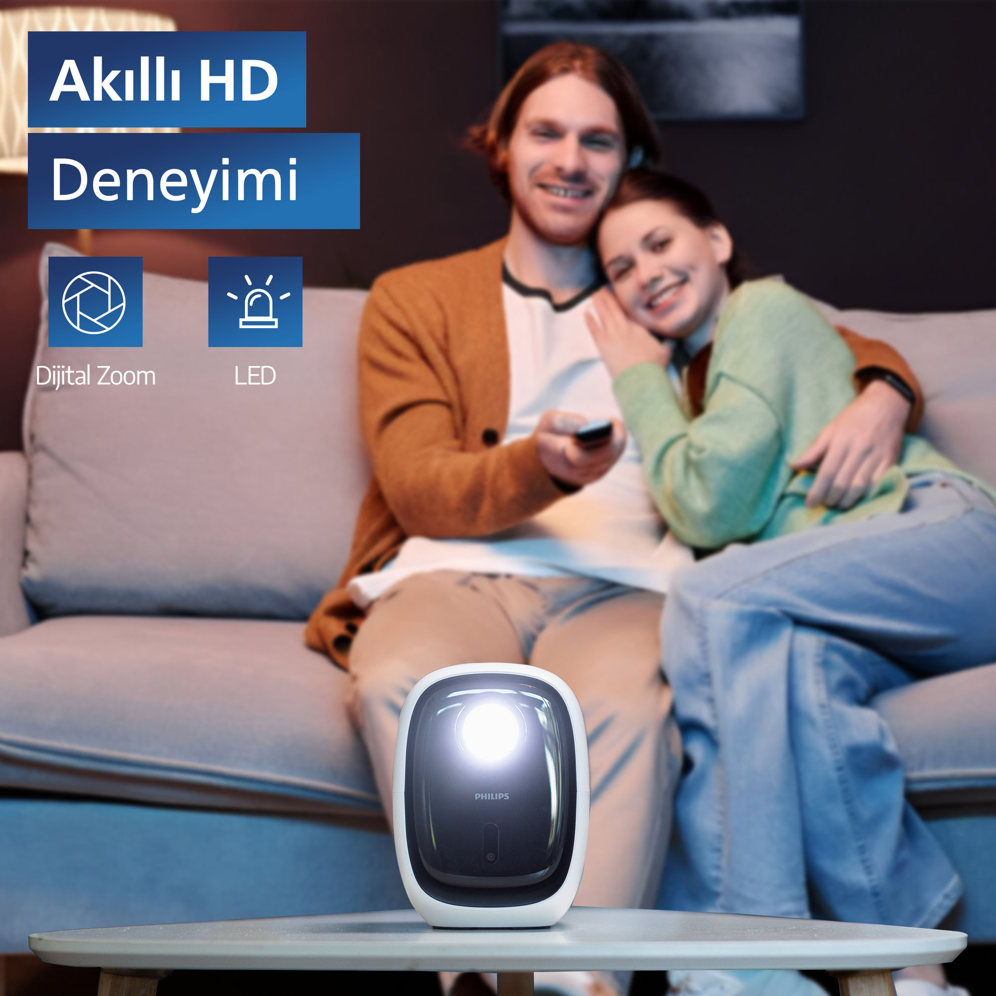 Arka planda bir kanepede oturan bir çift ile bir masada bir projektör. Dijital Yakınlaştırma ve LED simgeleri görünür.