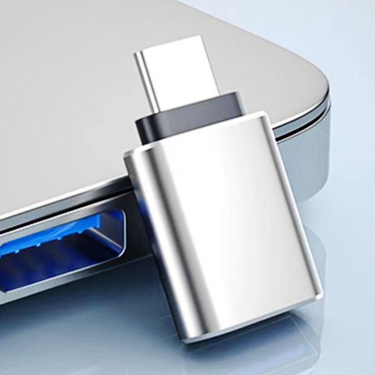 Srebrny adapter USB-C jest podłączony do srebrnego urządzenia. Adapter ma czarną sekcję. Tło jest rozmyte.