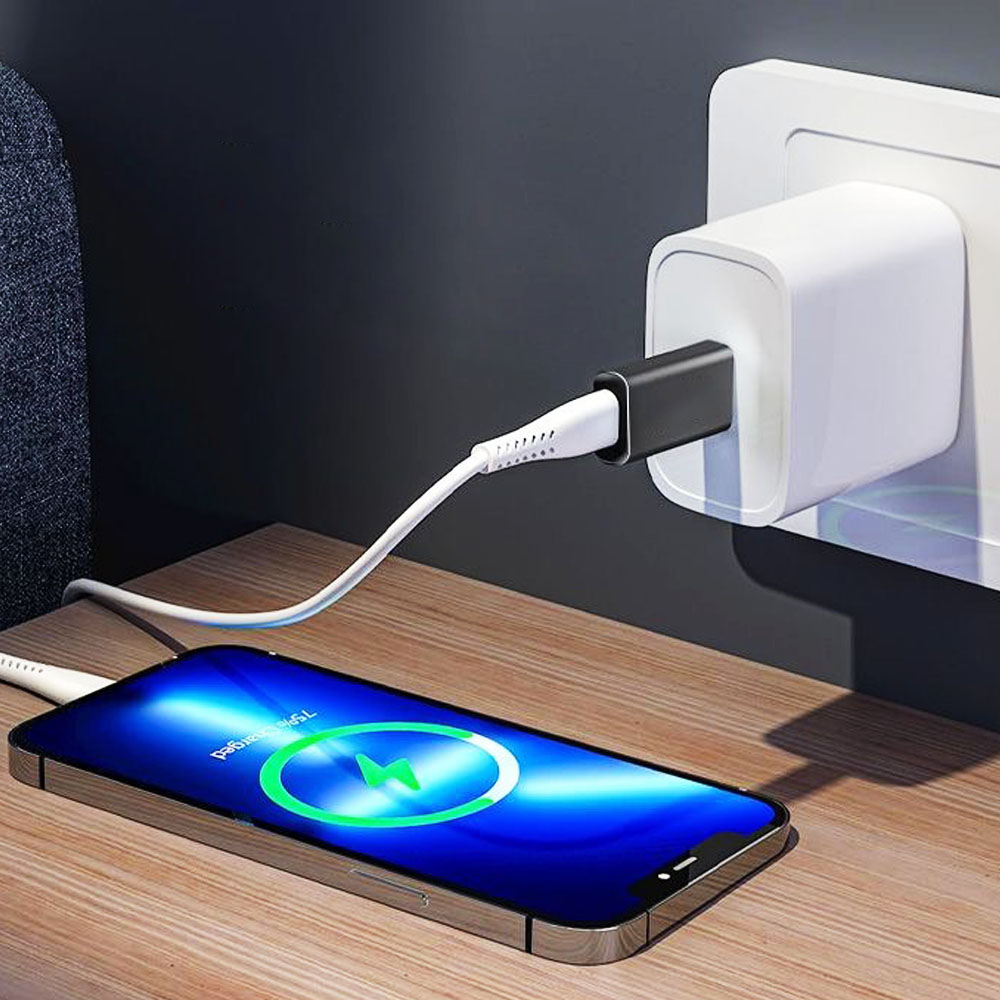 Telefon ładuje się białym kablem, podłączonym do ładowarki ściennej. Ekran pokazuje stan ładowania.