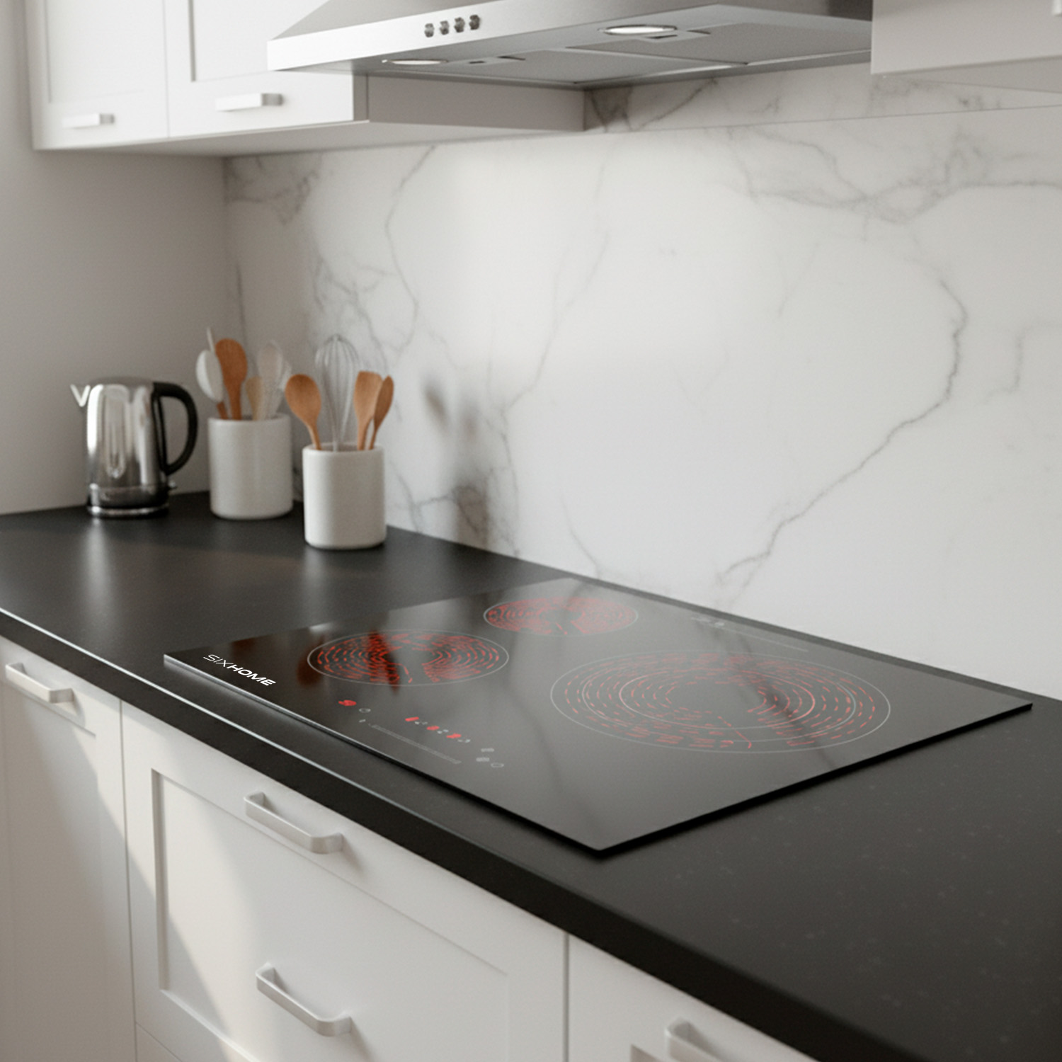 Cocina moderna con vitrocerámica negra, armarios blancos y salpicadero de mármol. Utensilios y una tetera a la vista.