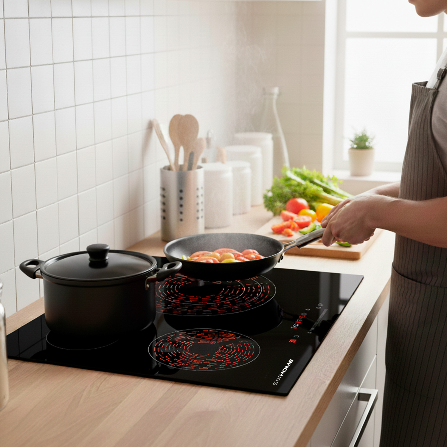Una persona cocina en una cocina moderna. Las verduras se cocinan en una sartén sobre una cocina eléctrica. Una olla negra está en la estufa.