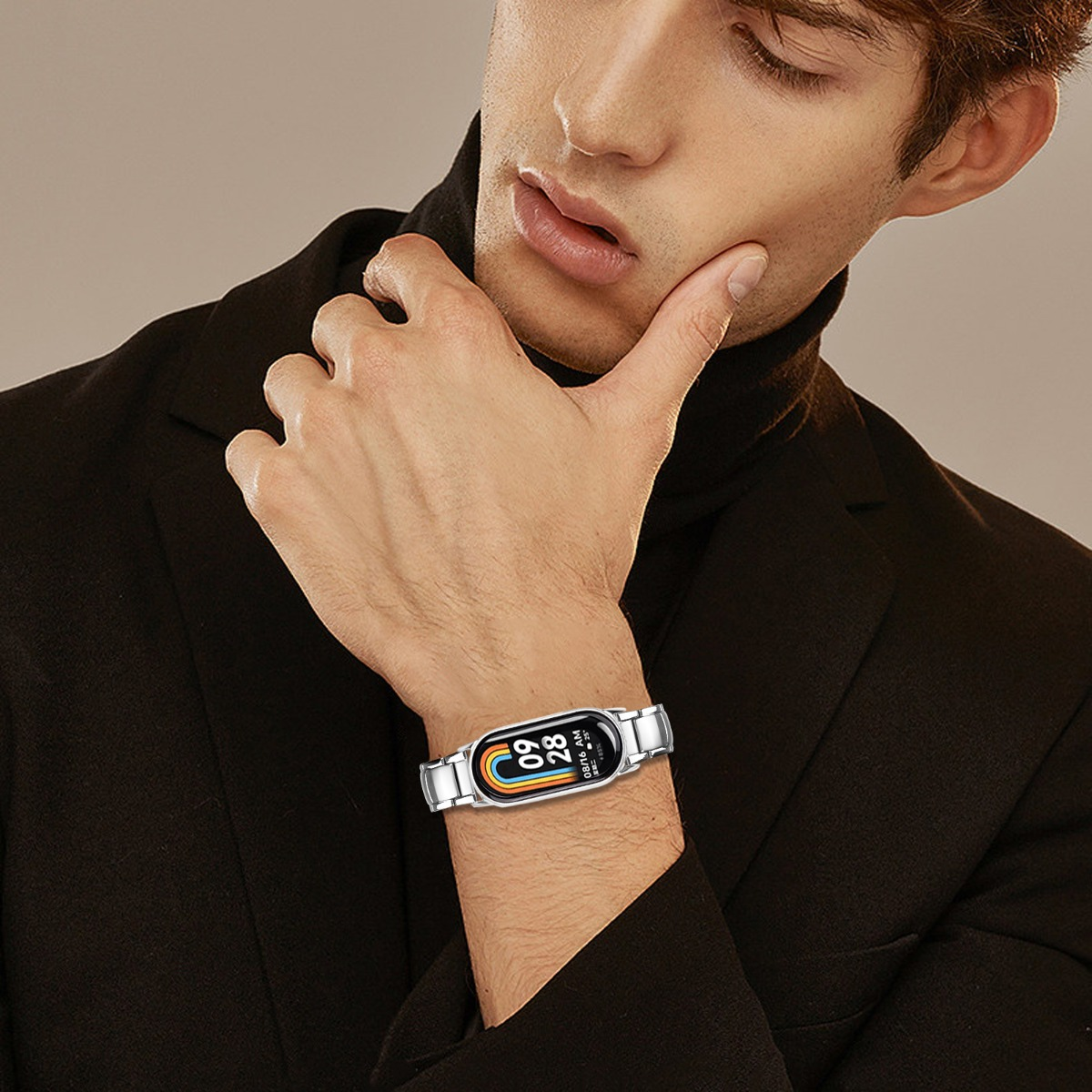 Ein Mann in einem schwarzen Blazer trägt eine silberne Smartwatch. Er berührt sein Gesicht mit der Hand. Die Uhr zeigt Zeit und Regenbogenfarben.
