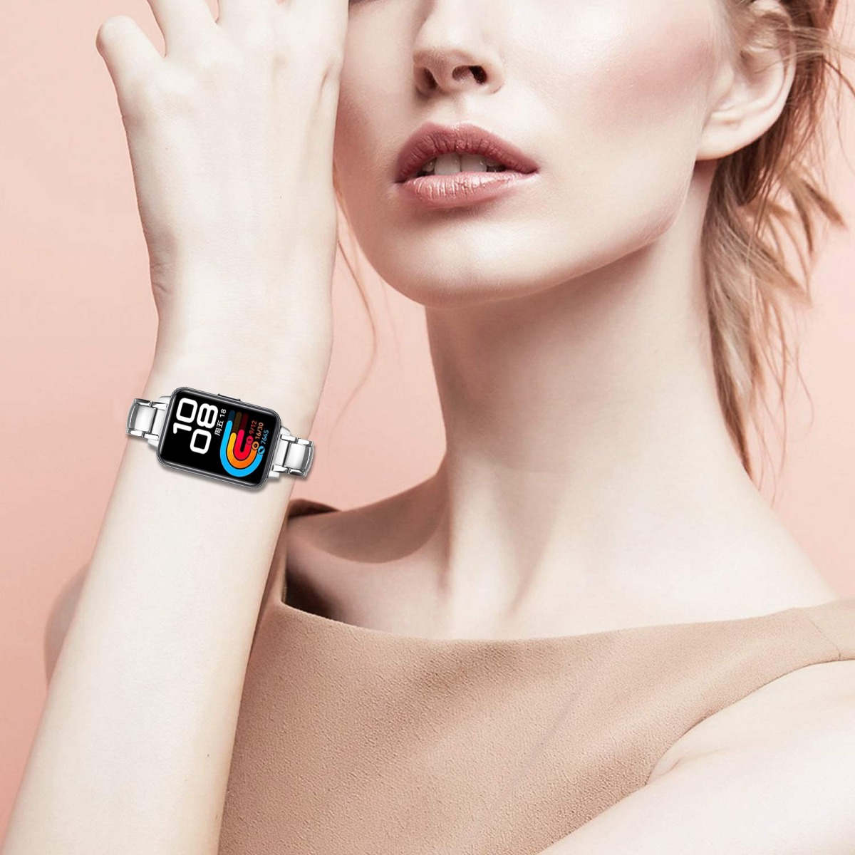 Eine Frau trägt eine Smartwatch am Handgelenk. Die Uhr zeigt Zeit- und Fitnessdaten an. Sie trägt ein braunes Oberteil.