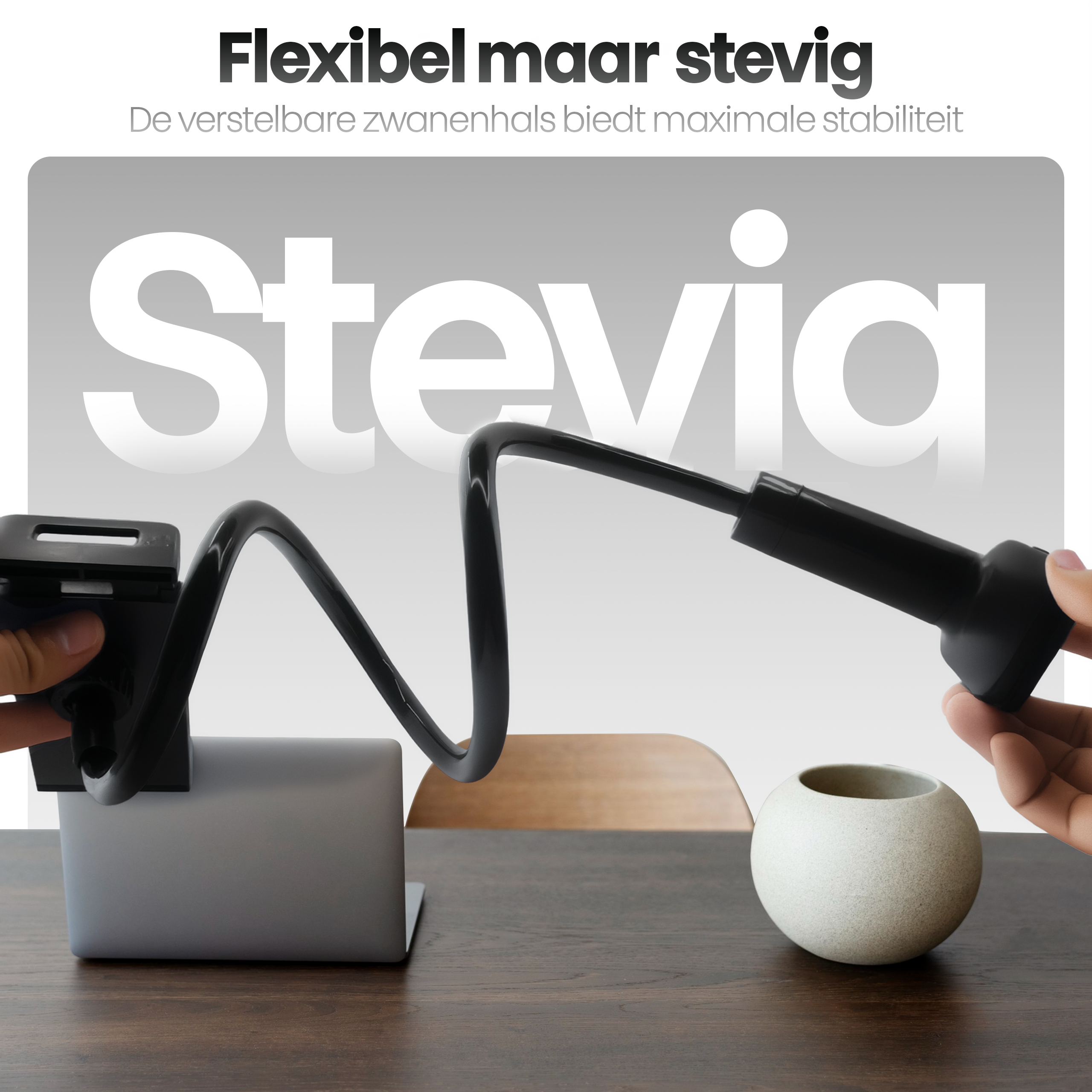Een flexibele zwarte telefoonhouder is verbonden met een laptop op een houten tafel. Rechts staat een witte vaas.