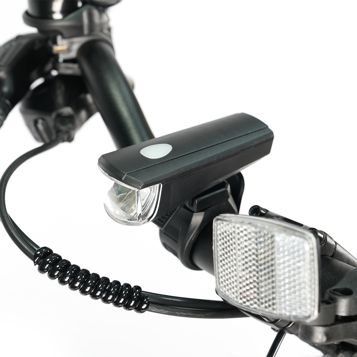 Zbliżenie kierownicy roweru z czarnym reflektorem i białym odblaskiem. Widoczny jest czarny kabel.