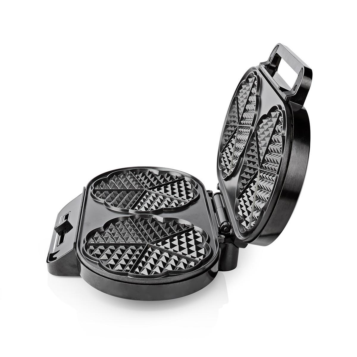 Una piastra per waffle nera, aperta, che mostra stampi a forma di cuore. È su una superficie bianca. La maniglia è visibile.