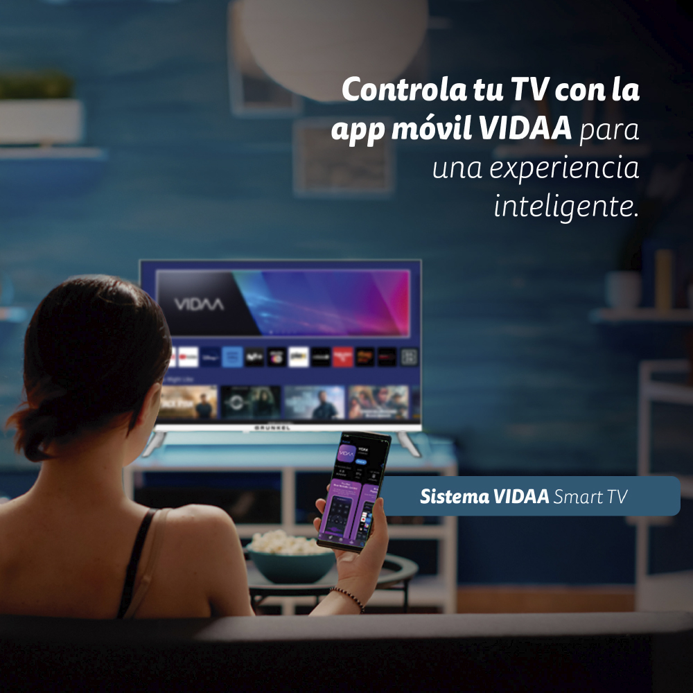 Una mujer usa un teléfono para controlar un televisor con la aplicación VIDAA. El televisor muestra el logo VIDAA. Palomitas en la mesa.