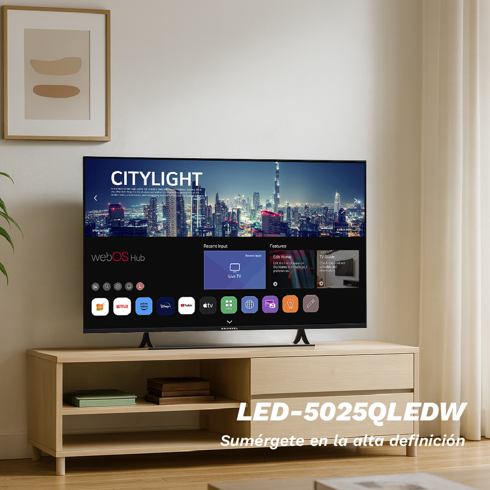 Un televisor muestra un paisaje urbano. Debajo, un mueble de madera sostiene el televisor. Los iconos de las aplicaciones son visibles en la pantalla. Un cuadro enmarcado cuelga arriba.