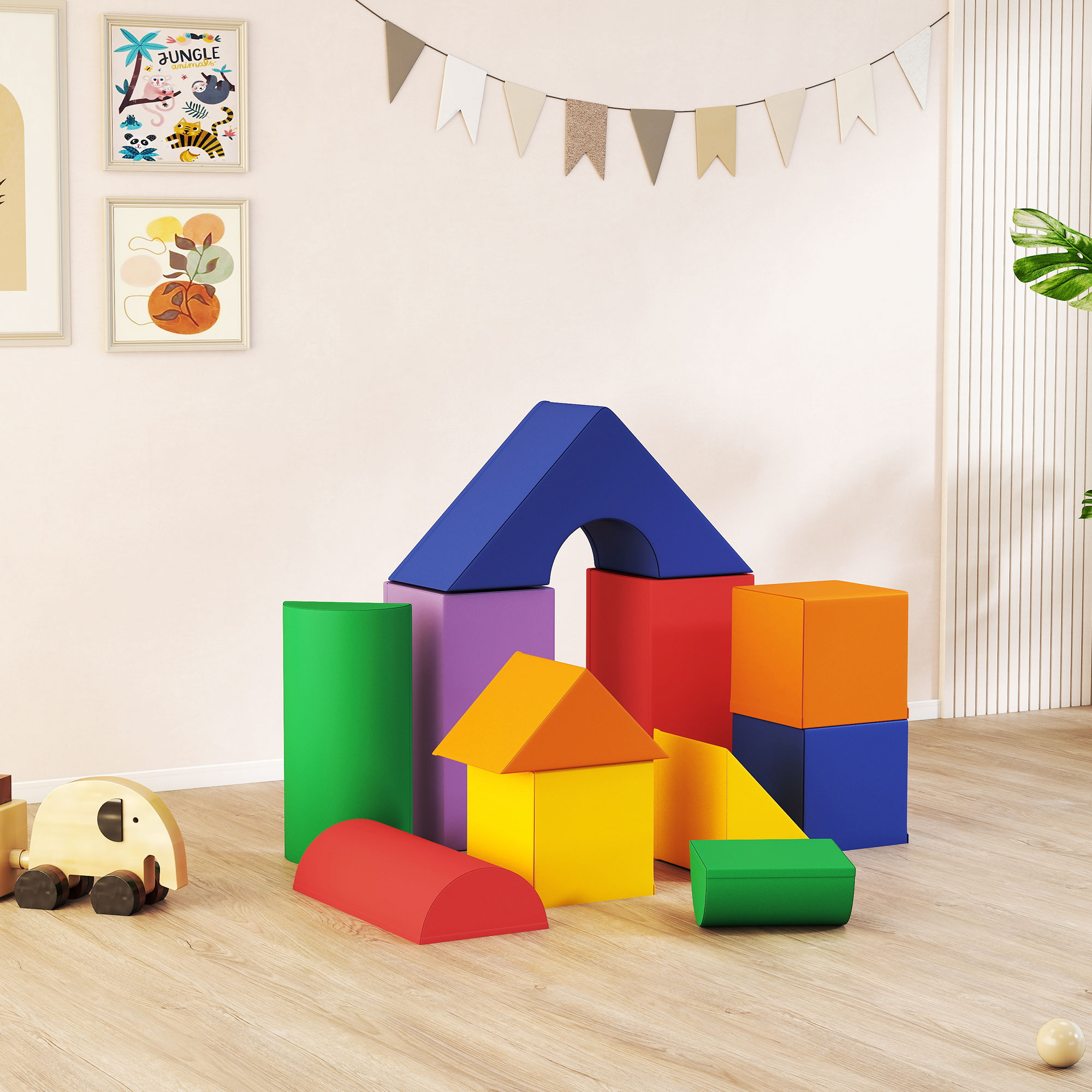 Un'area giochi colorata con blocchi di schiuma impilati. Sono visibili una forma di casa, un semicerchio e un elefante giocattolo. Arte murale sullo sfondo.