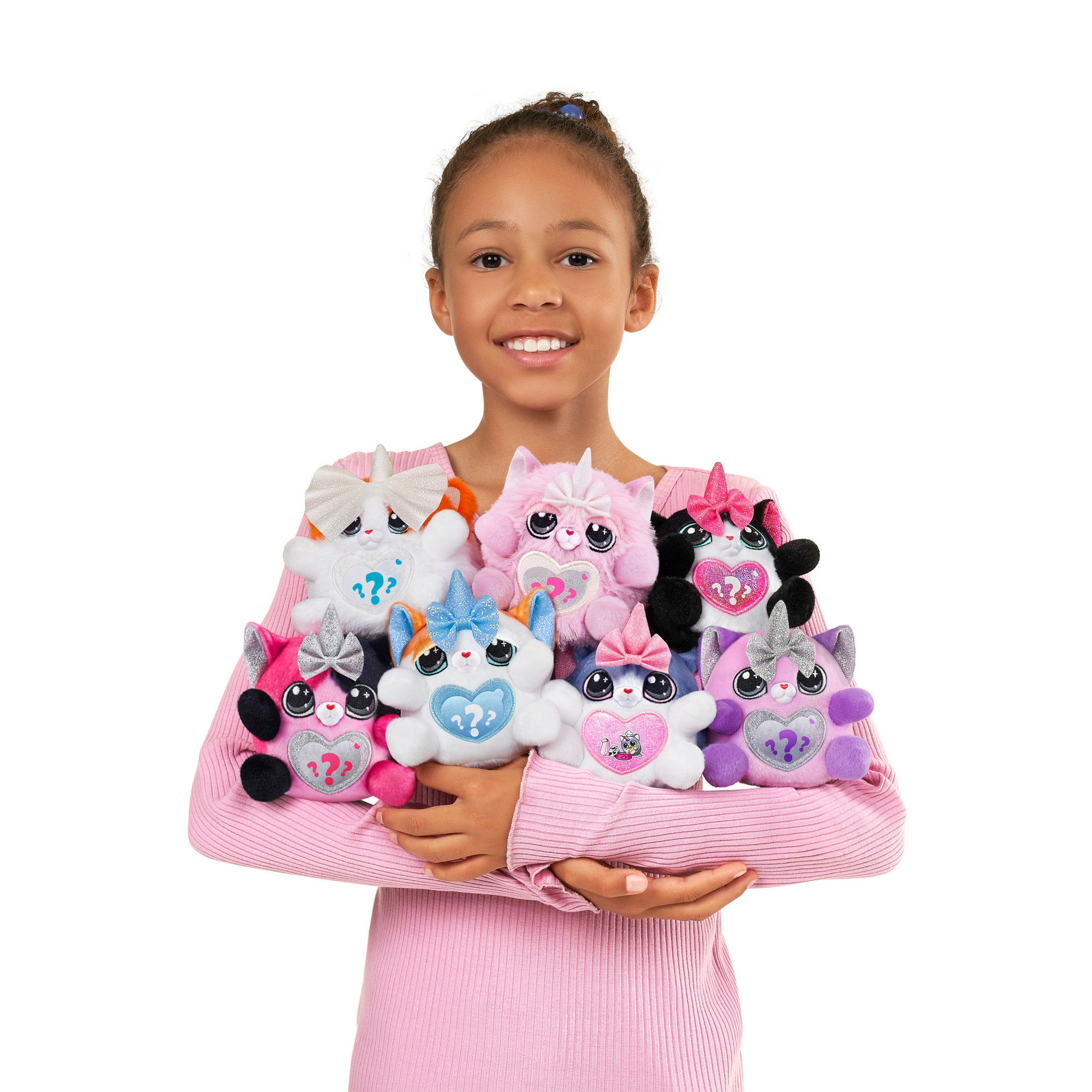 Ein Mädchen hält mehrere Plüschkatzenspielzeuge. Die Katzen sind unterschiedlich gefärbt und haben Herzen und Schleifen. Das Mädchen lächelt.
