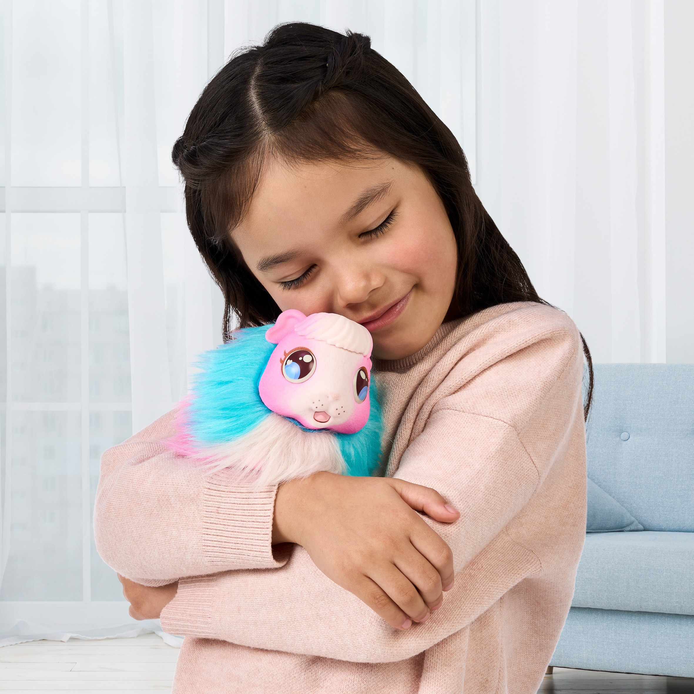 Una ragazza abbraccia un peluche. Il giocattolo è rosa, blu e bianco. La ragazza indossa un maglione rosa con gli occhi chiusi.
