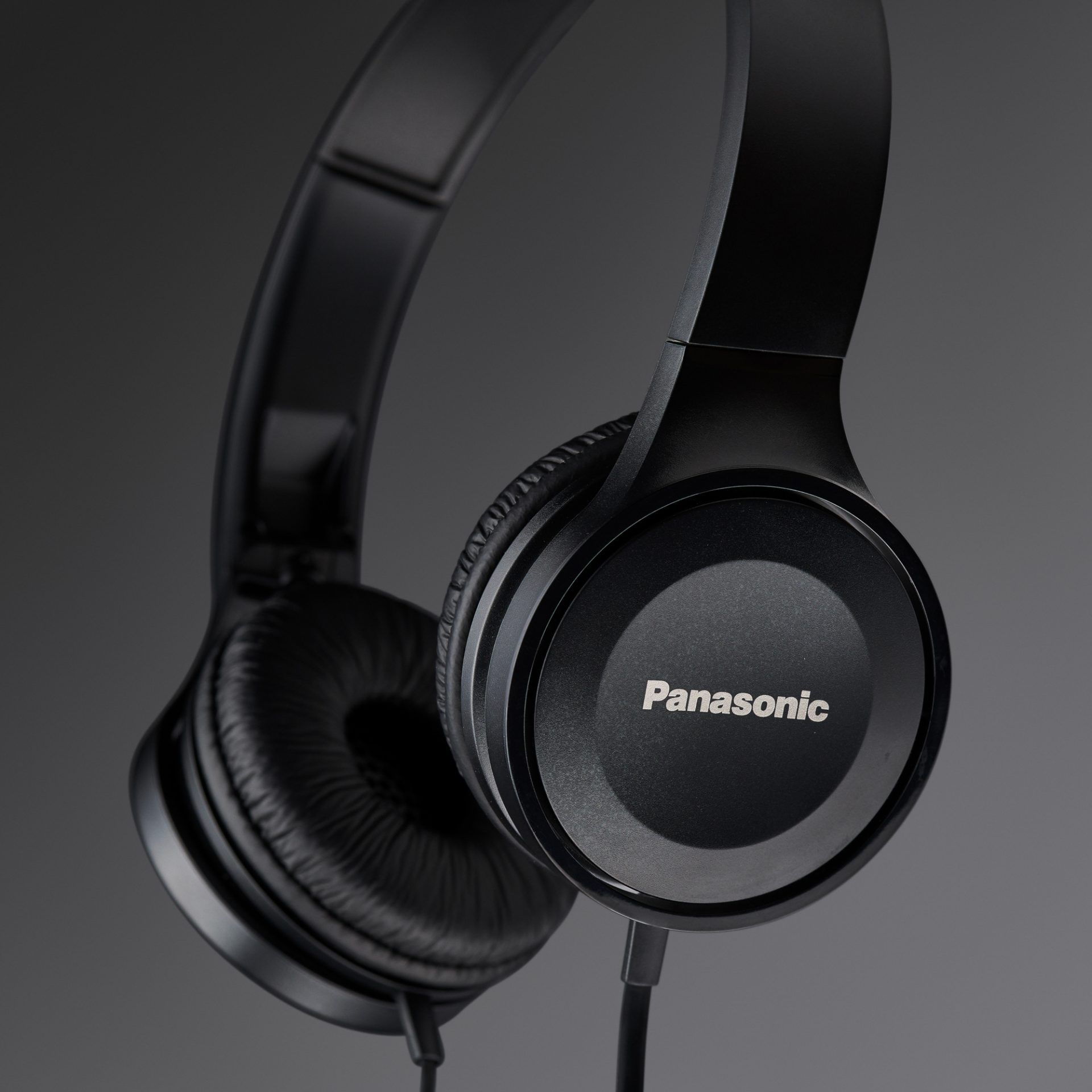 Schwarze Panasonic-Kopfhörer auf grauem Hintergrund. Der Markenname ist auf dem Ohrmuschel sichtbar.