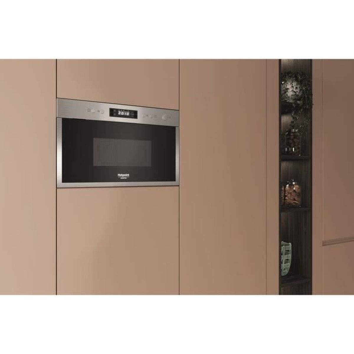 Cucina moderna con forno a microonde integrato e ripiano in legno scuro con oggetti decorativi.