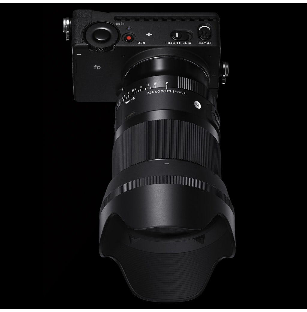 Een zwarte camera met een lens. De lens is een Sigma 50mm 1:1.4 DG DN 72. De camera staat op een zwarte achtergrond.