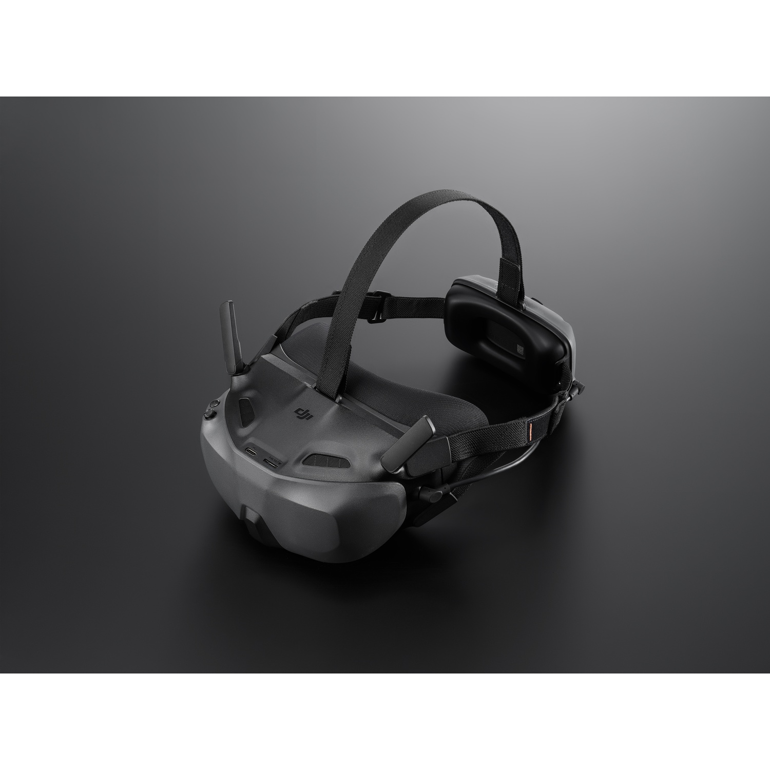 Ein schwarzes VR-Headset mit Kopfband, das auf einer dunklen Oberfläche liegt. Das Headset hat Antennen und Ohrmuscheln.