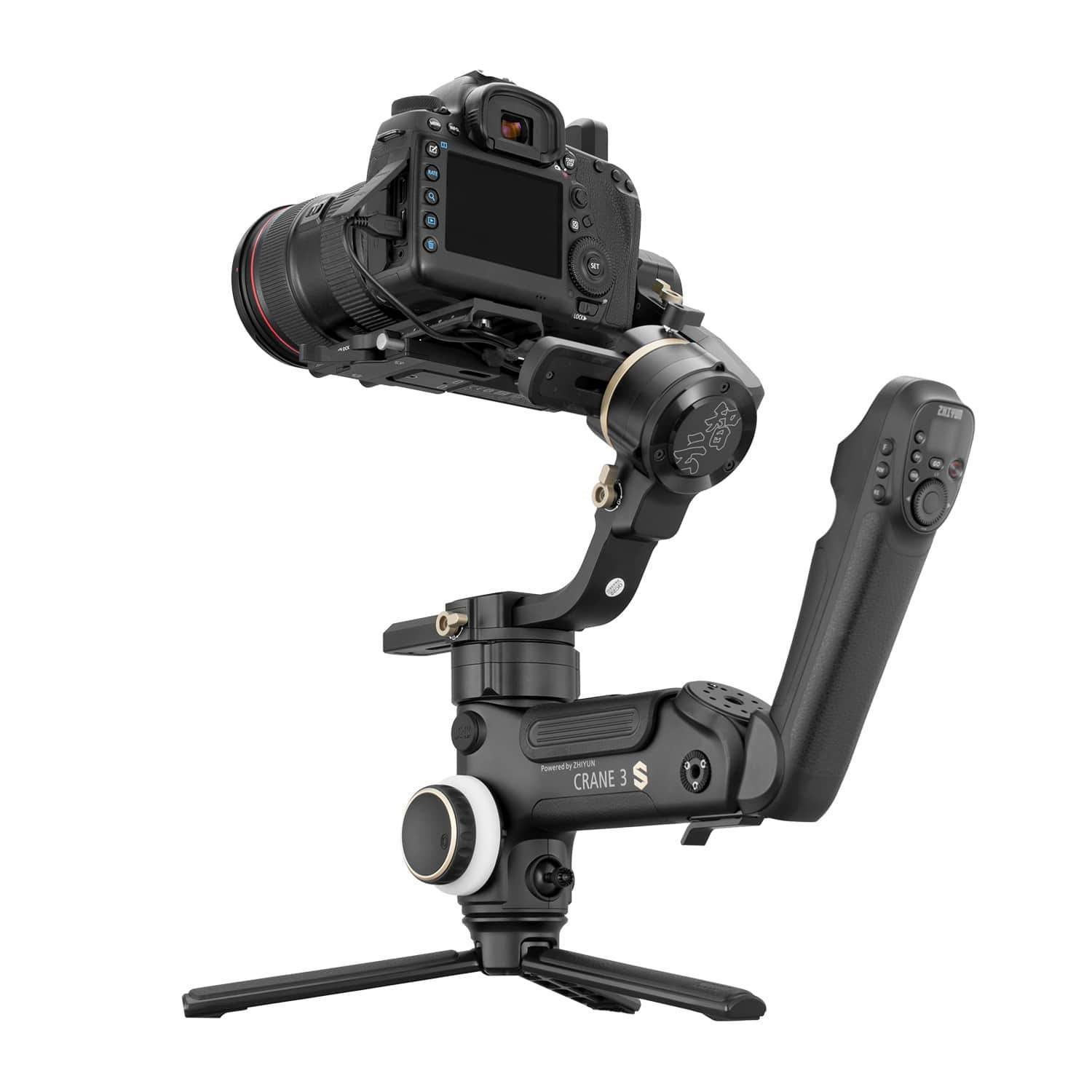 Una fotocamera nera è montata su uno stabilizzatore gimbal. Lo stabilizzatore ha un'impugnatura ed è supportato da un piccolo treppiede.