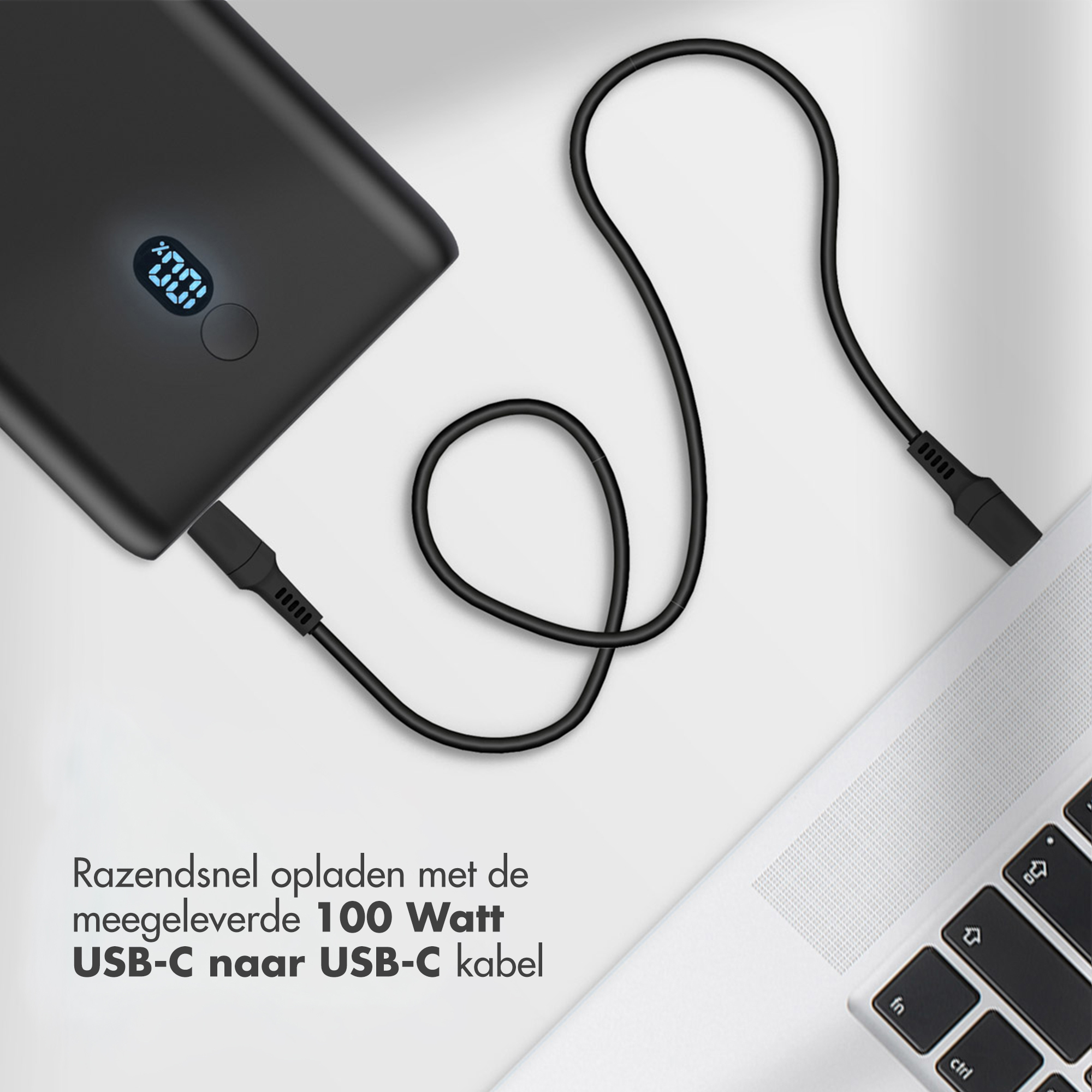 Batterie externe noire avec câble USB-C connecté à un ordinateur portable. La batterie affiche 100%. Fond blanc.