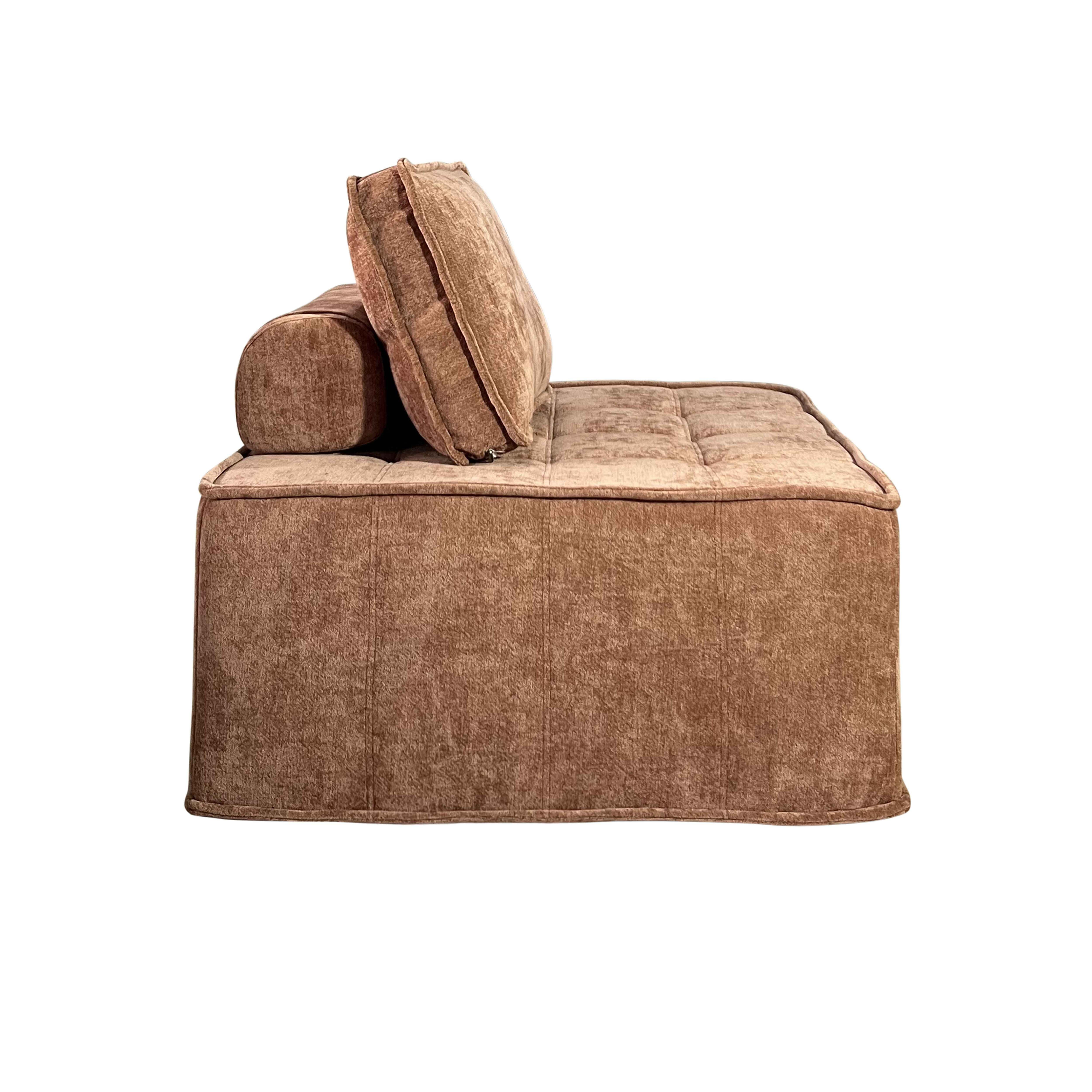 Ein braunes, modernes Sofa. Es hat eine quadratische Basis, eine Rückenlehne und ein zylindrisches Kissen.