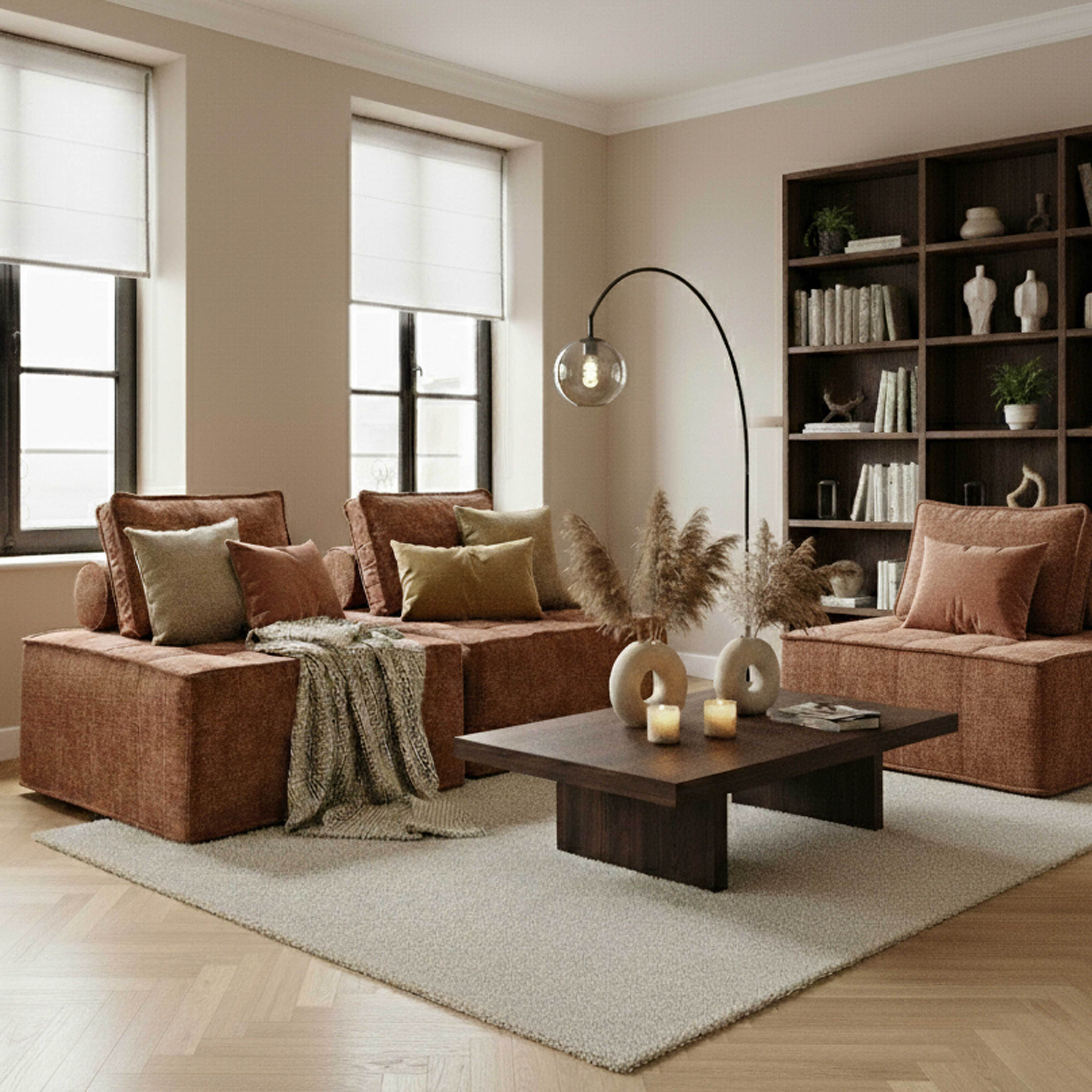Wohnzimmer mit braunen Sofas, einem Couchtisch, einem Teppich, einem Bücherregal und großen Fenstern.