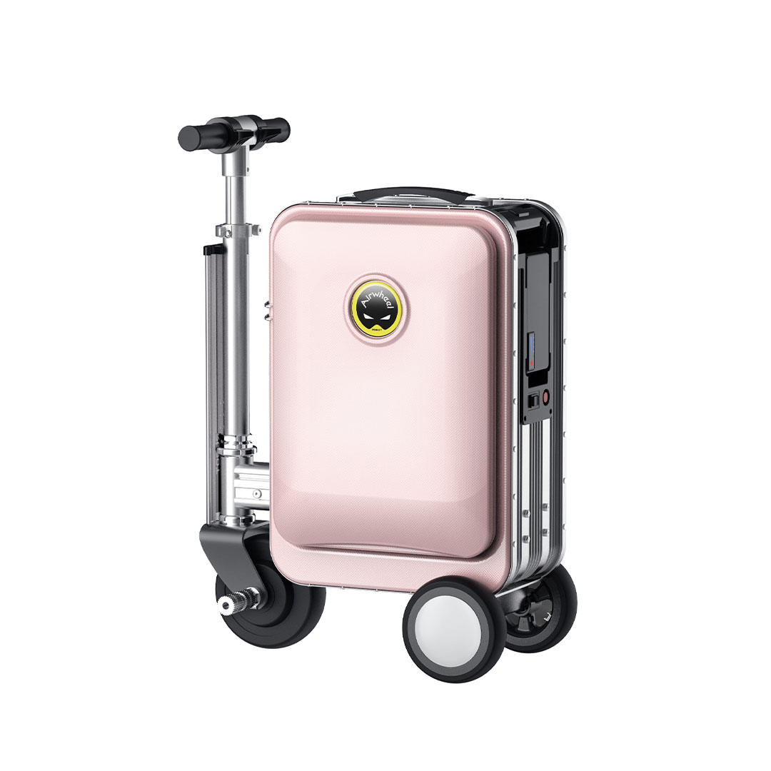 Pembe bir bavul scooter. Bir tutacağı, önde iki küçük tekerlek ve arkada iki daha büyük tekerleği var. Marka logosu görünür.