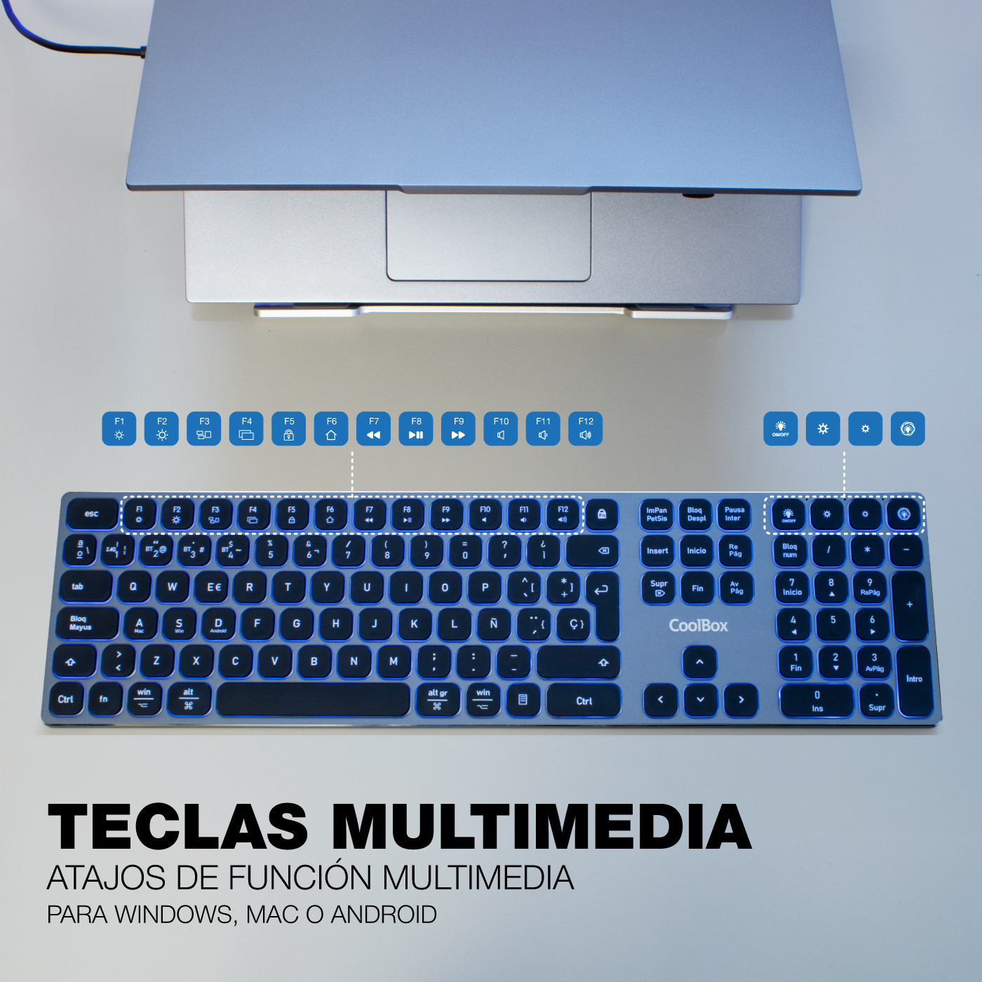 Un teclado plateado con teclas retroiluminadas azules, un portátil y texto que dice 'Teclas multimedia'.