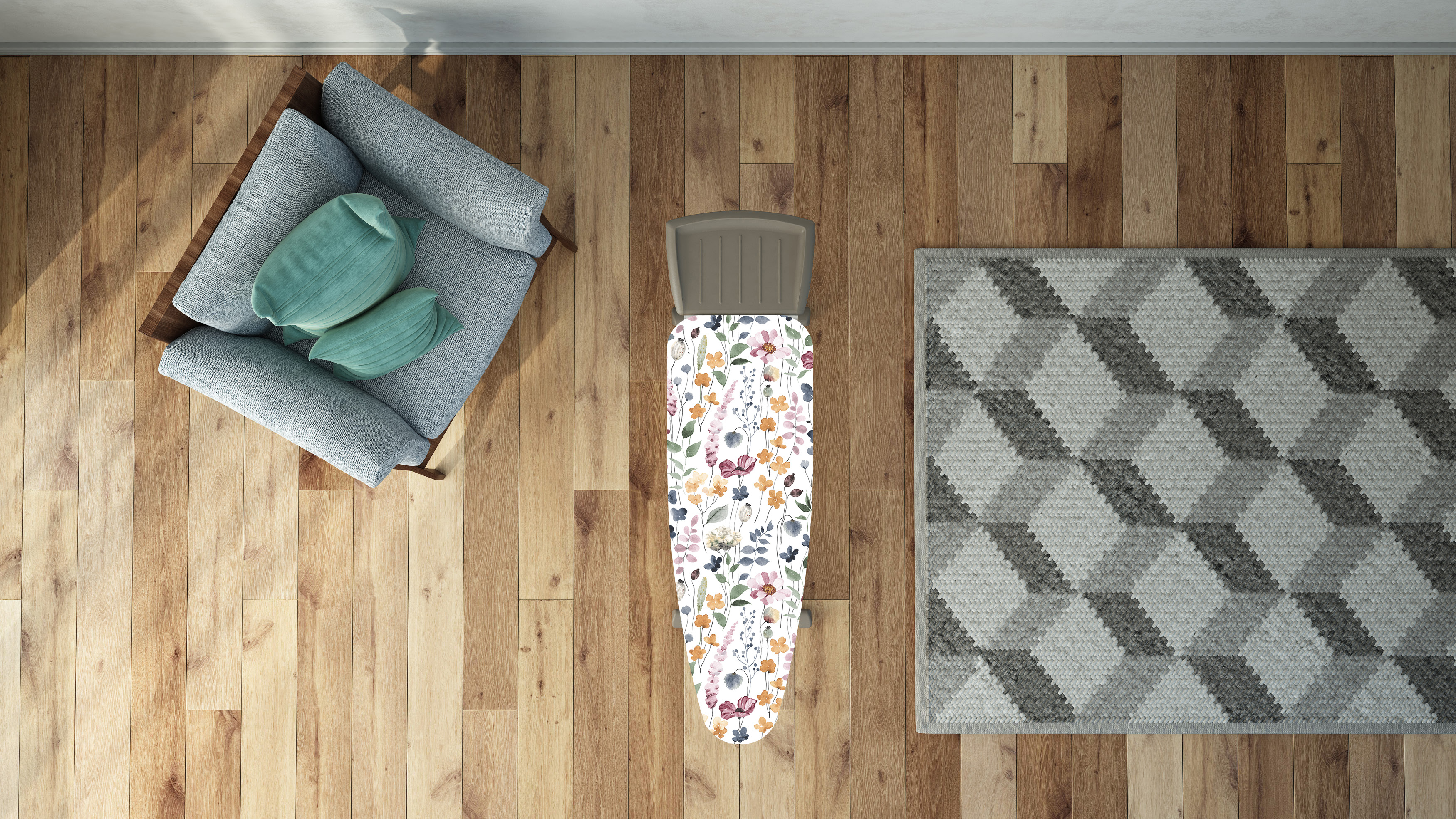 Draufsicht auf einen Raum. Enthält einen grauen Sessel mit zwei grünen Kissen, ein Bügelbrett mit Blumenmuster und einen gemusterten Teppich.
