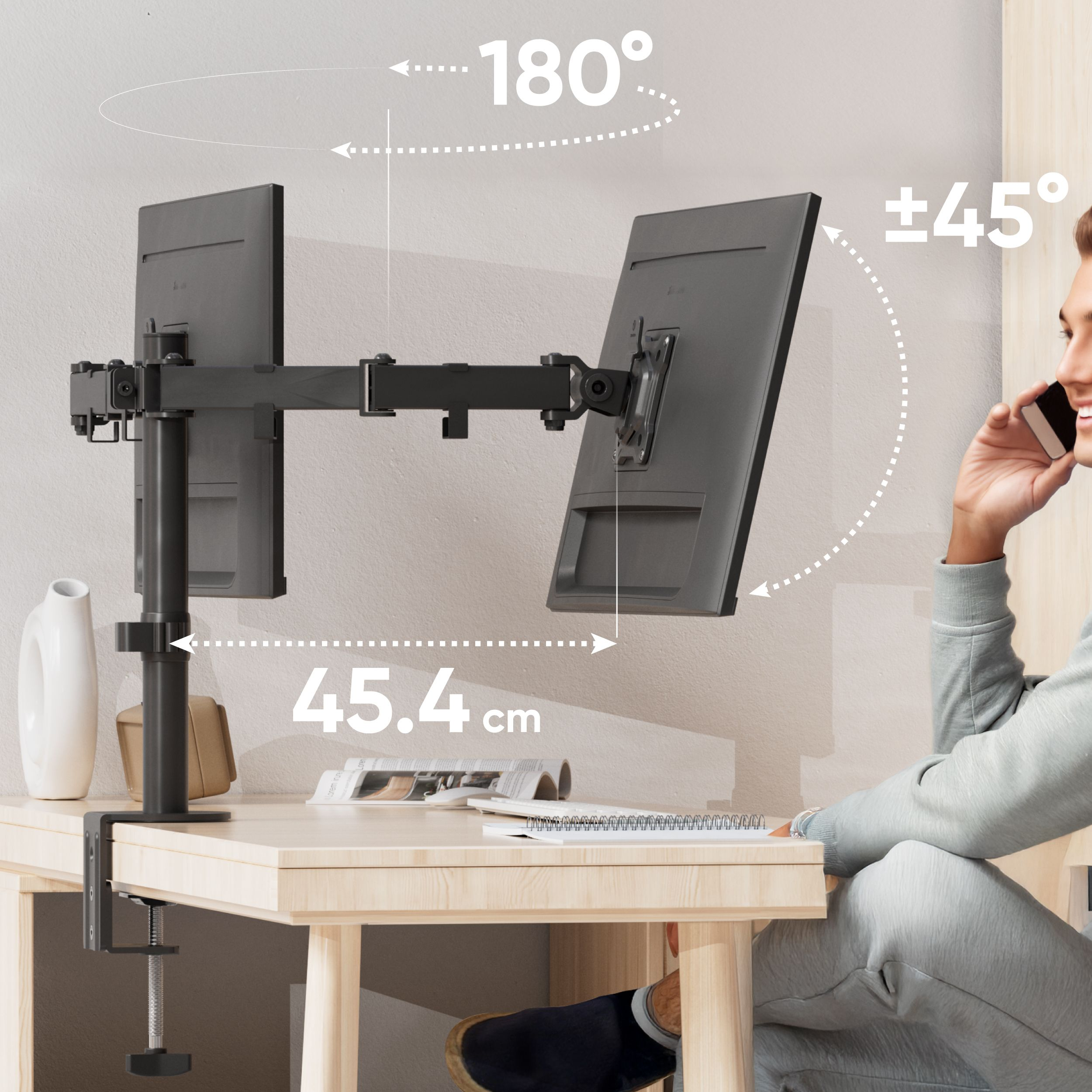 Un uomo al telefono accanto a un braccio a doppio monitor con due monitor. Il braccio ruota di 180 gradi.