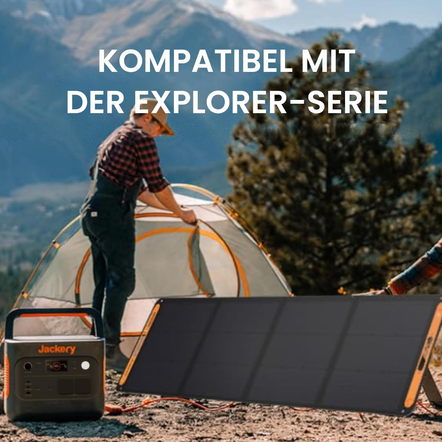 Ein Mann baut ein Zelt in der Nähe einer Jackery-Powerstation und eines Solarpanels auf, mit Bergen im Hintergrund.